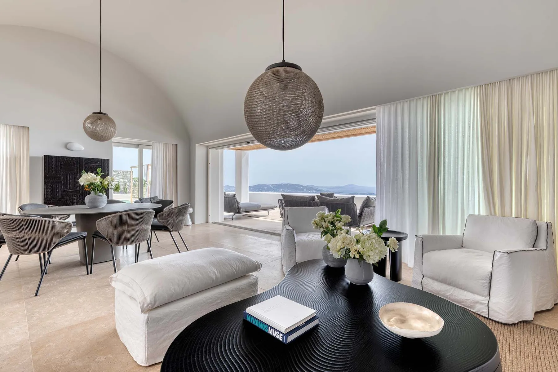 A bright living room opens onto a terrace, with seating and a dining area.
