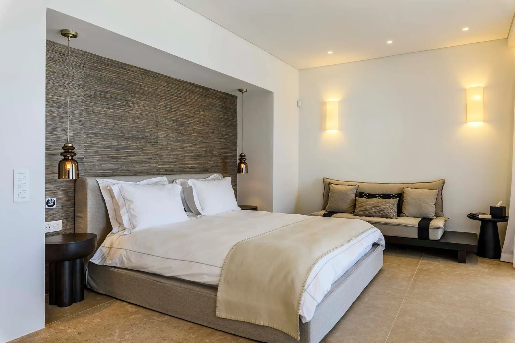 A bedroom with a large bed and a seating area against the far wall.