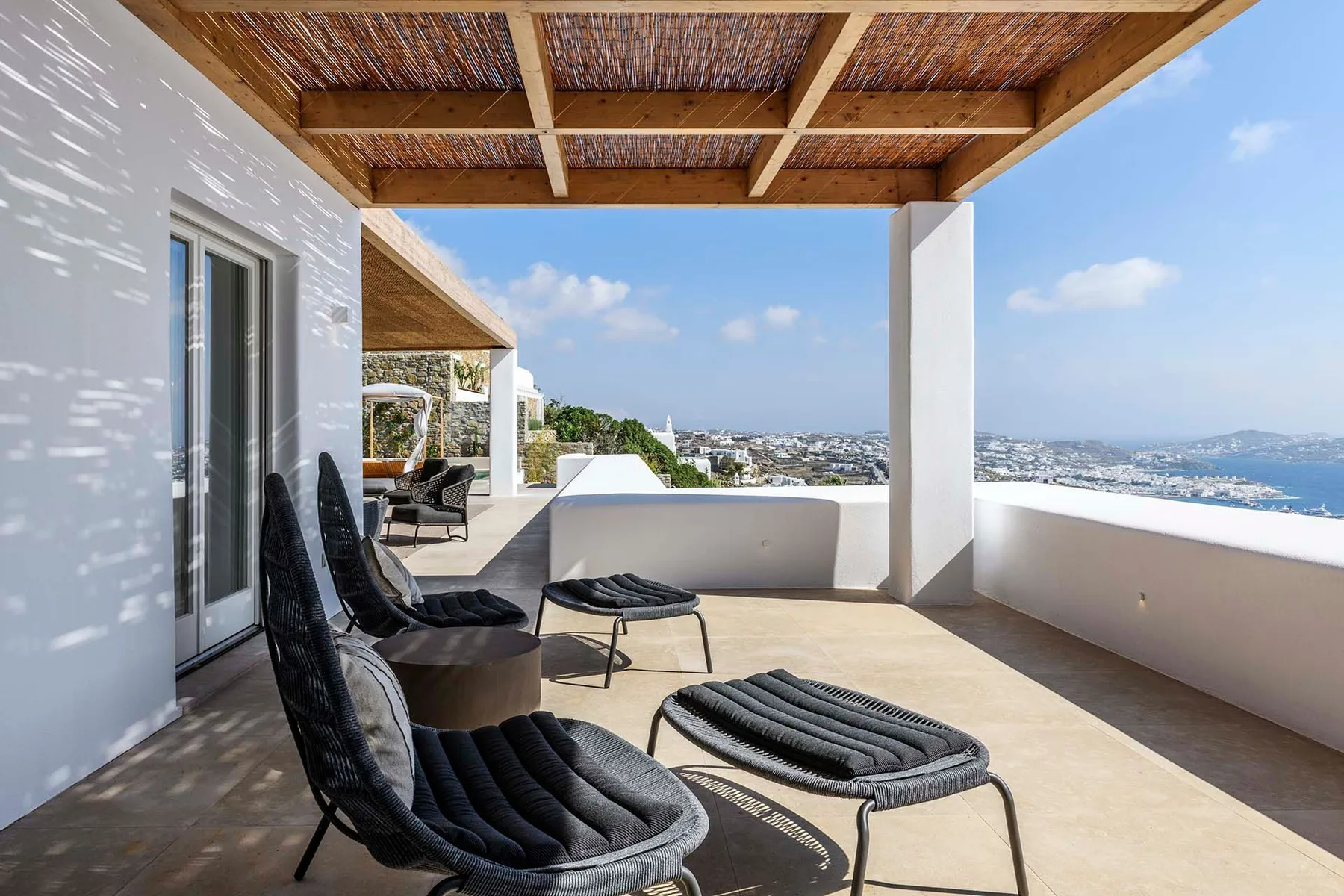 A rooftop terrace with lounge seating and a broad view of the coast.