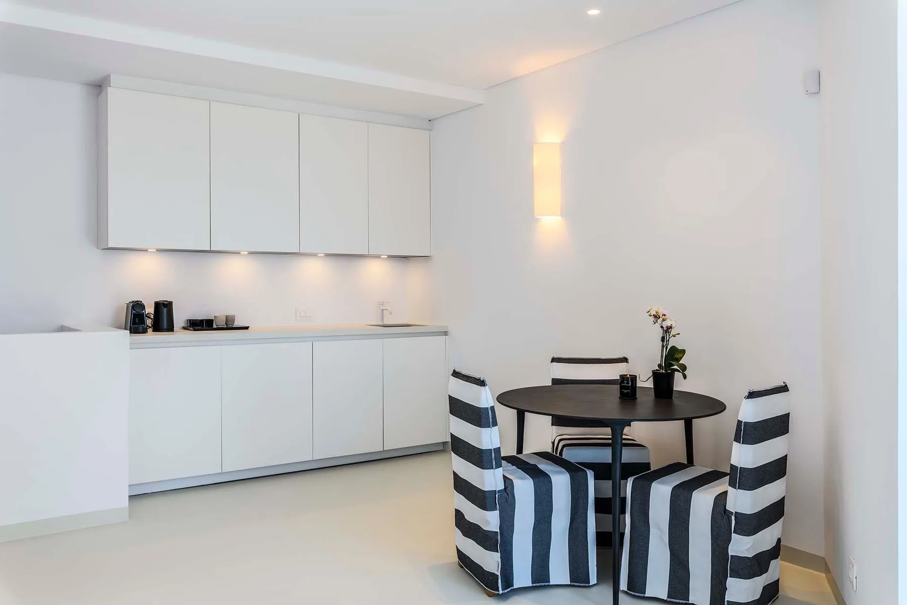 A bright kitchen and dining area with a round table and striped seating.