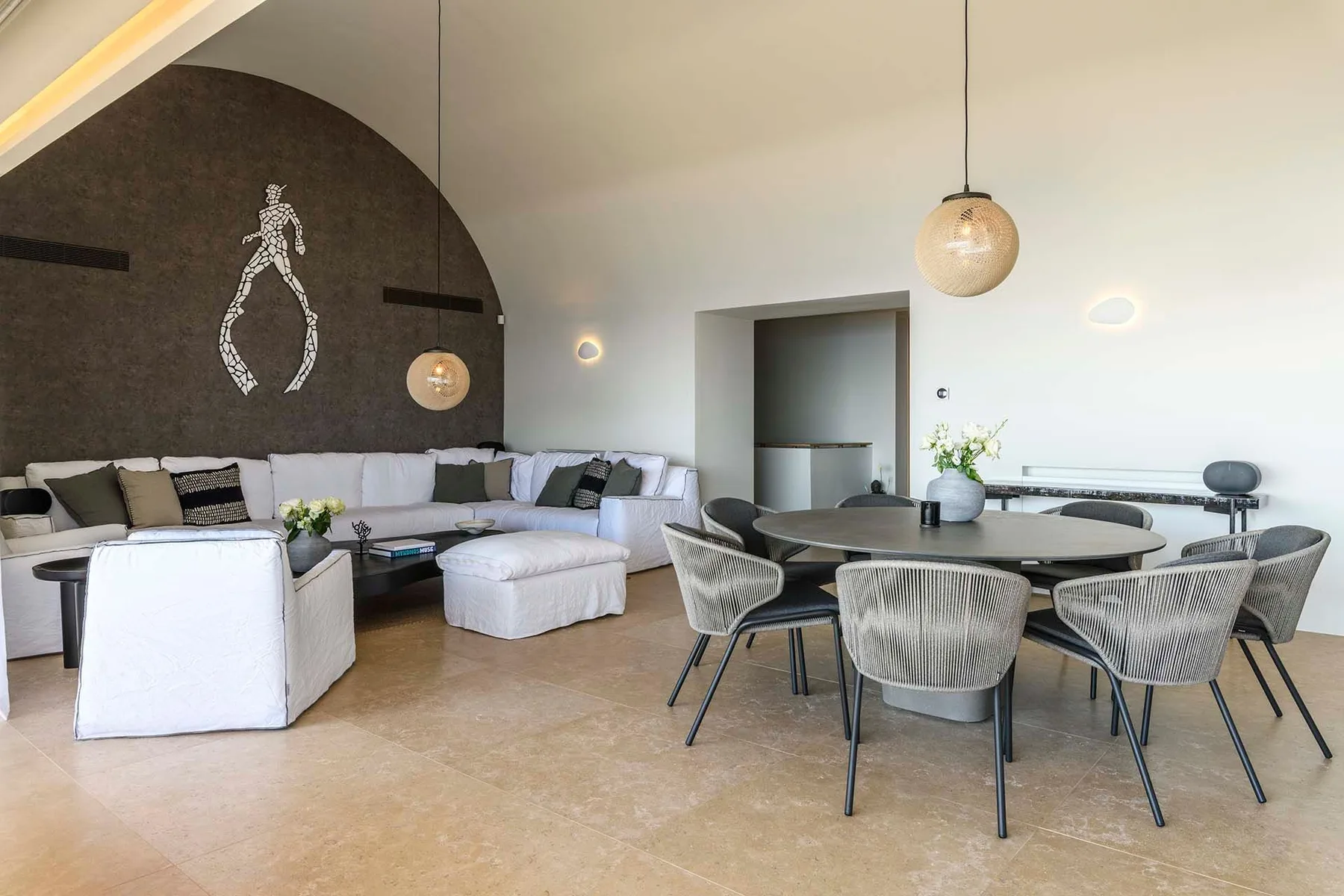 A modern lounge and dining area with a curved sectional seating arrangement and round table.