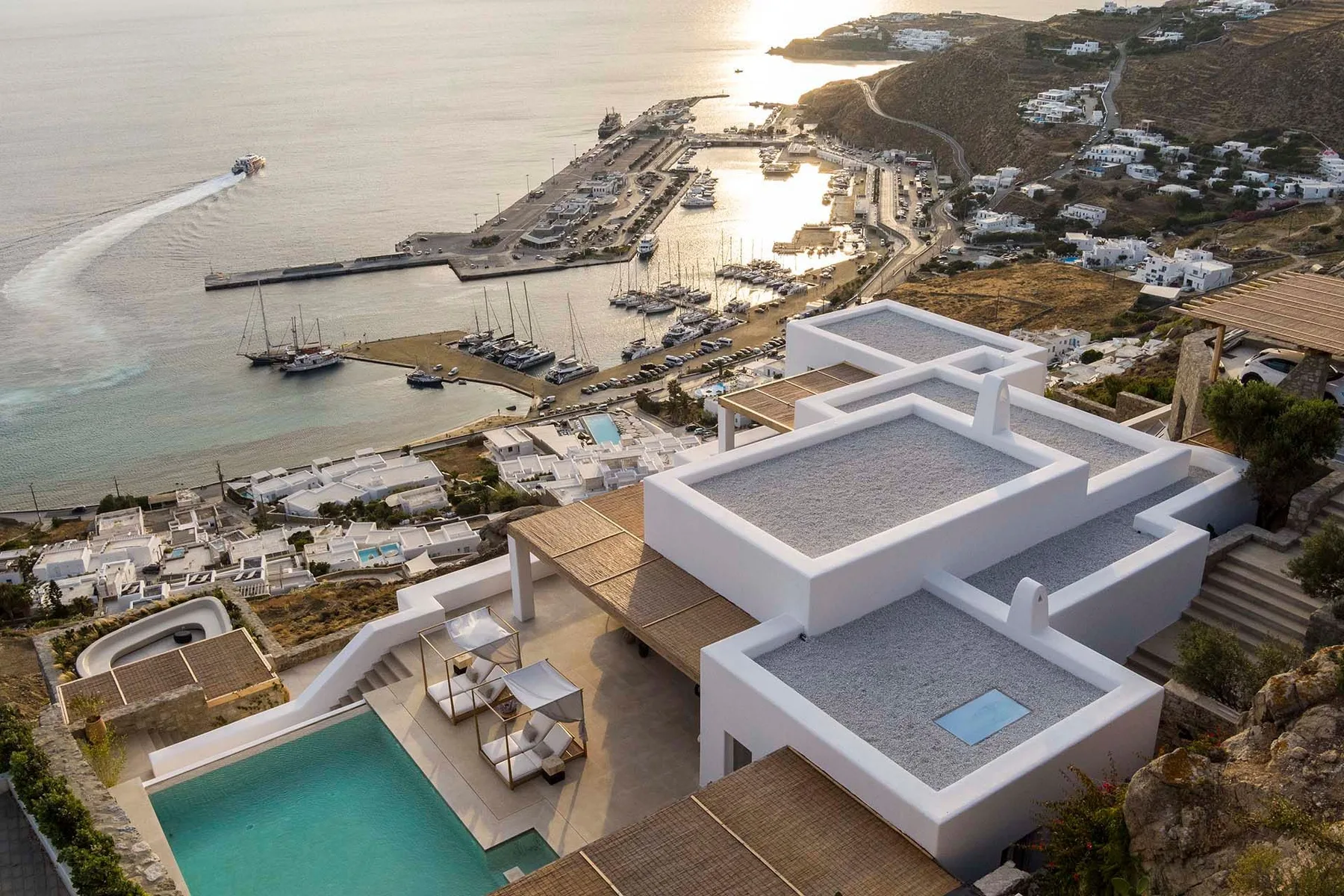 Aerial view of a modern coastal property with a pool overlooking a marina.