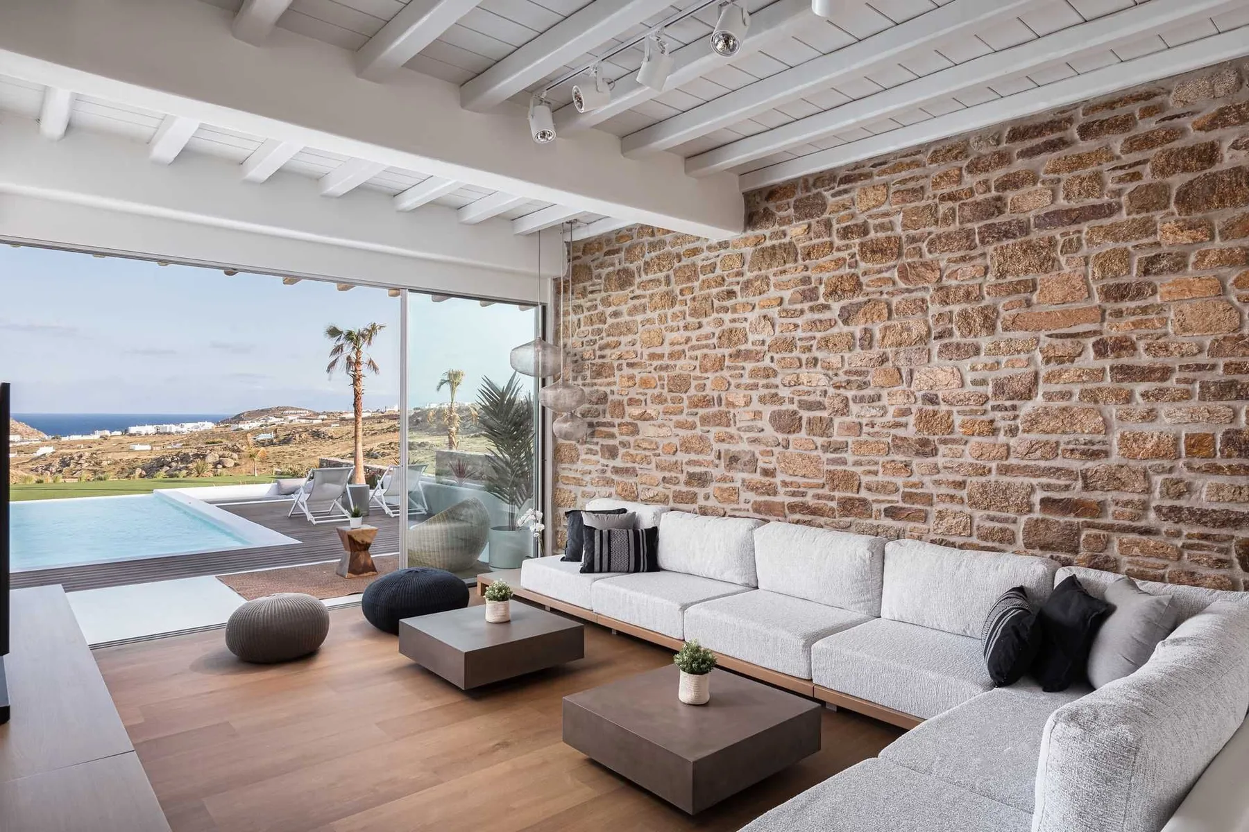 Una sala de estar con asientos junto a puertas de vidrio, con vistas a una piscina y al mar.
