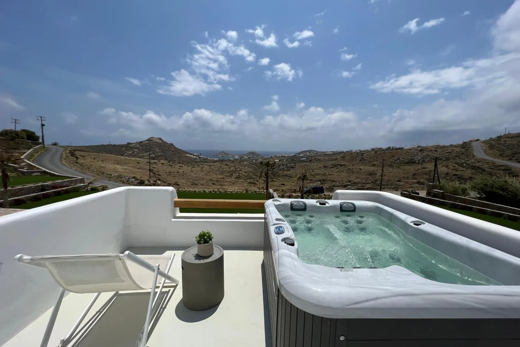 Una bañera de hidromasaje al aire libre está en una terraza con vistas a un paisaje seco y ondulado.