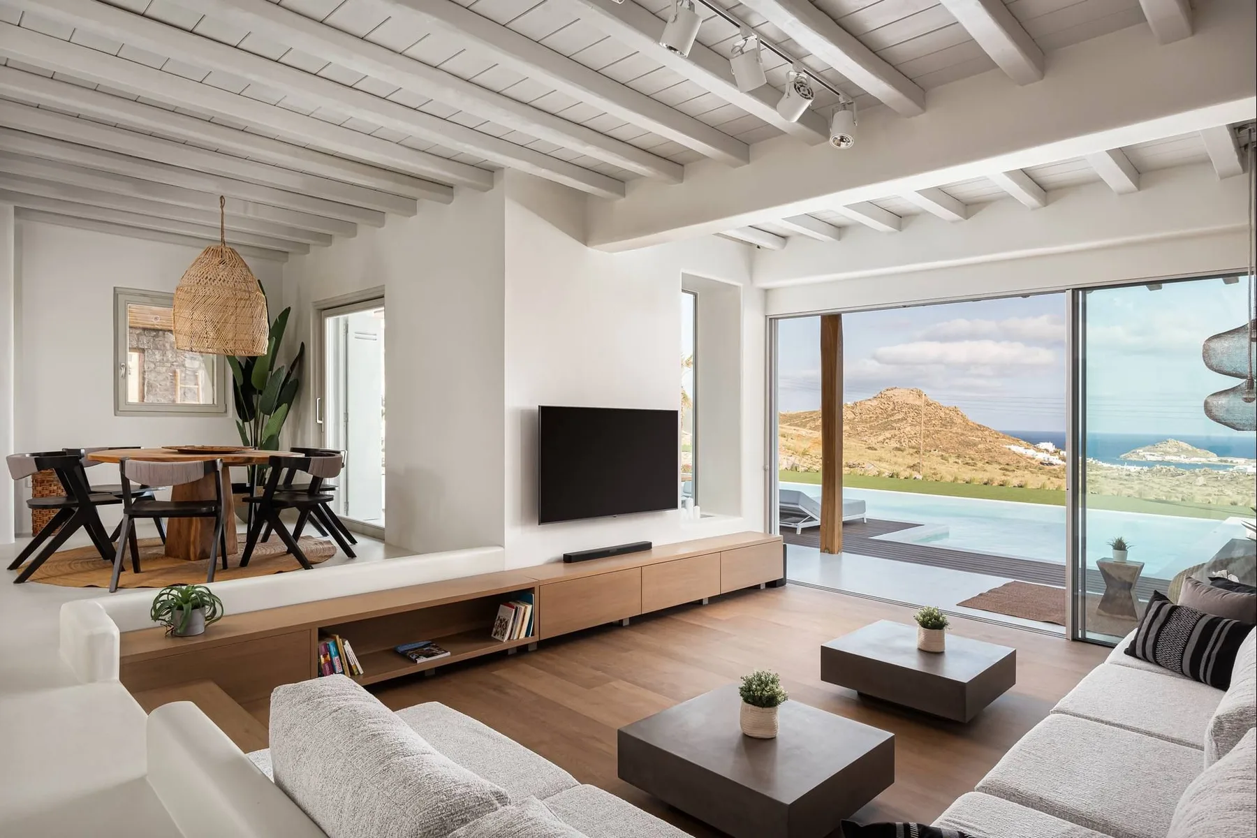 Una luminosa sala de estar con asientos, comedor y amplias ventanas con vistas al mar.