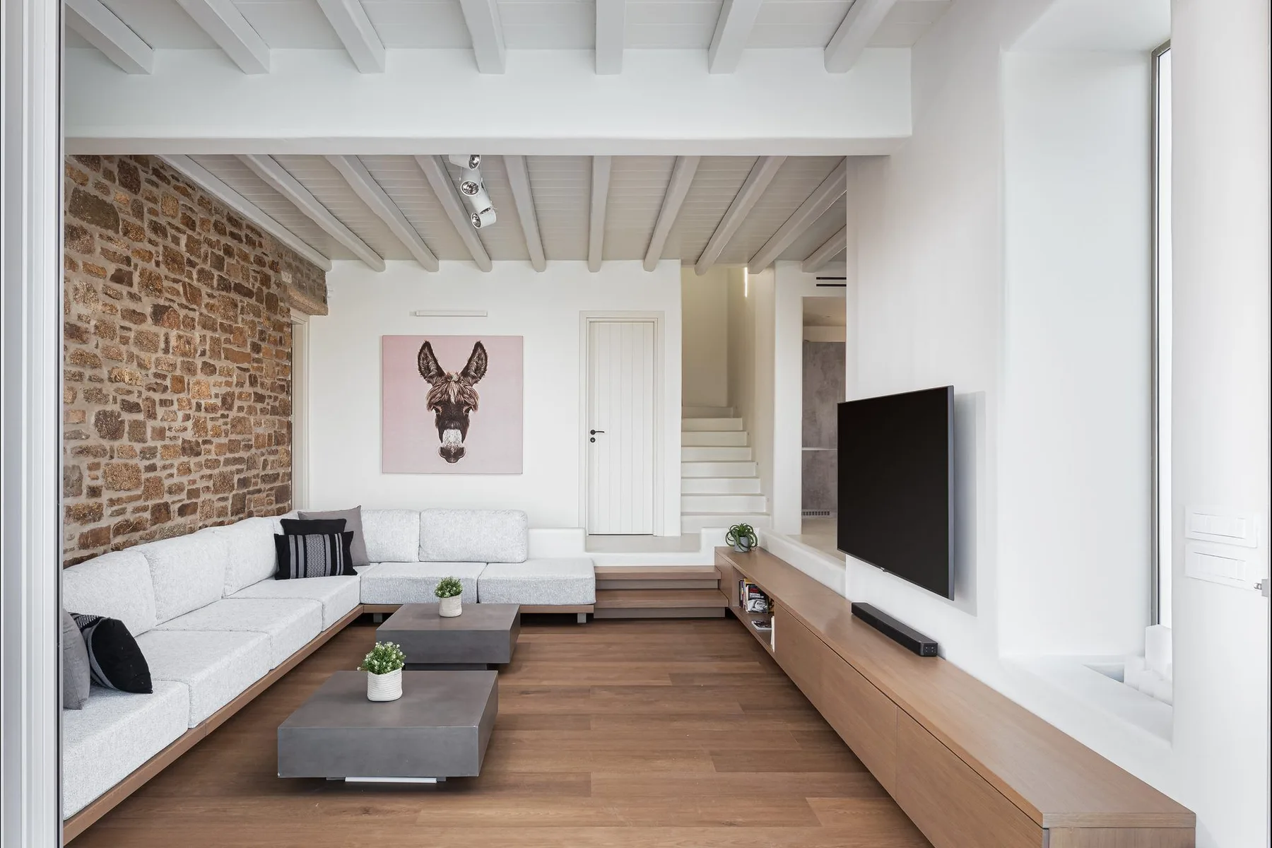 Una sala de estar con asientos seccionales, un televisor y una pared de piedra expuesta.