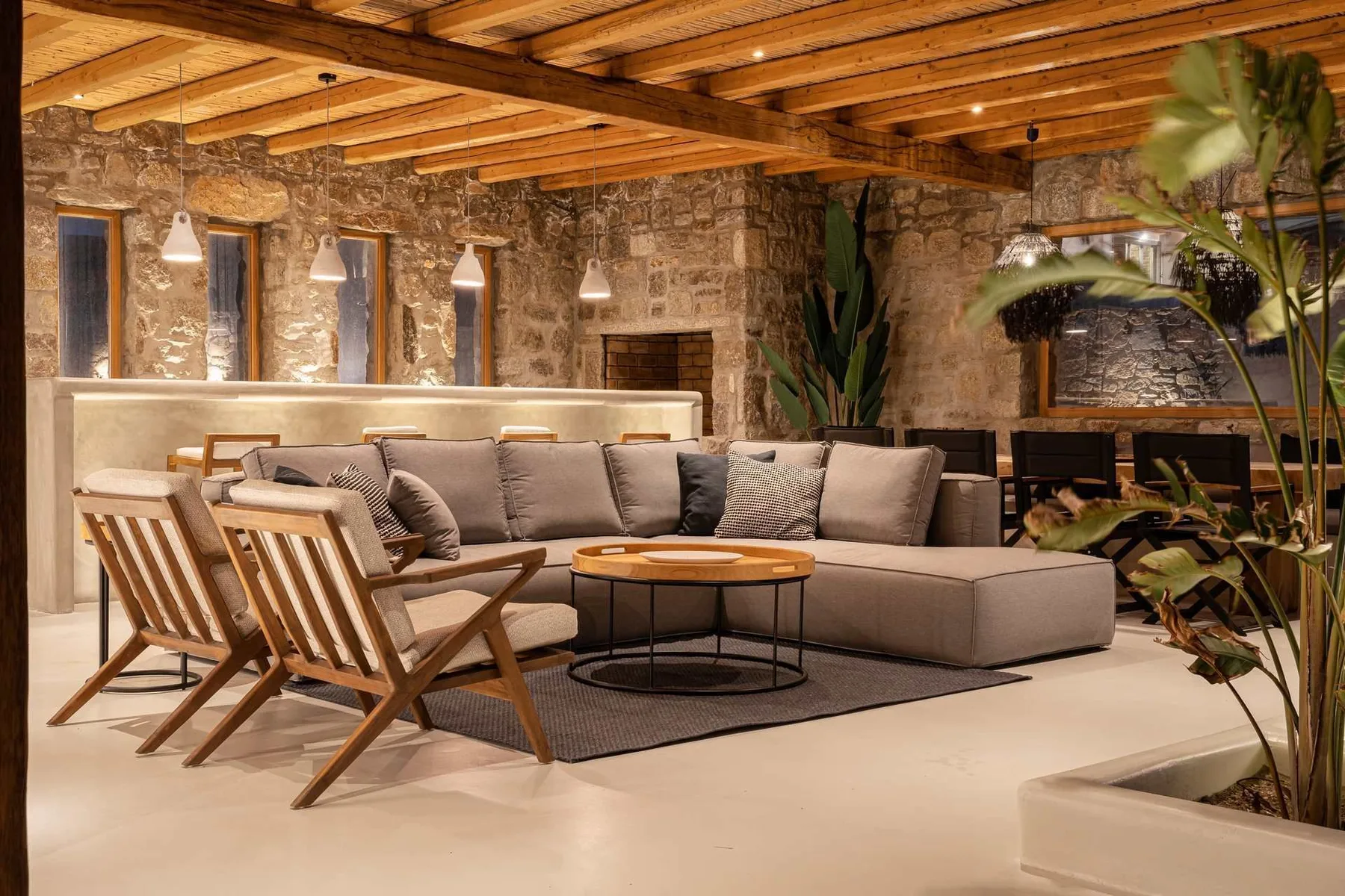 Una zona de estar con sofá seccional, mesas bajas y sillas de madera.