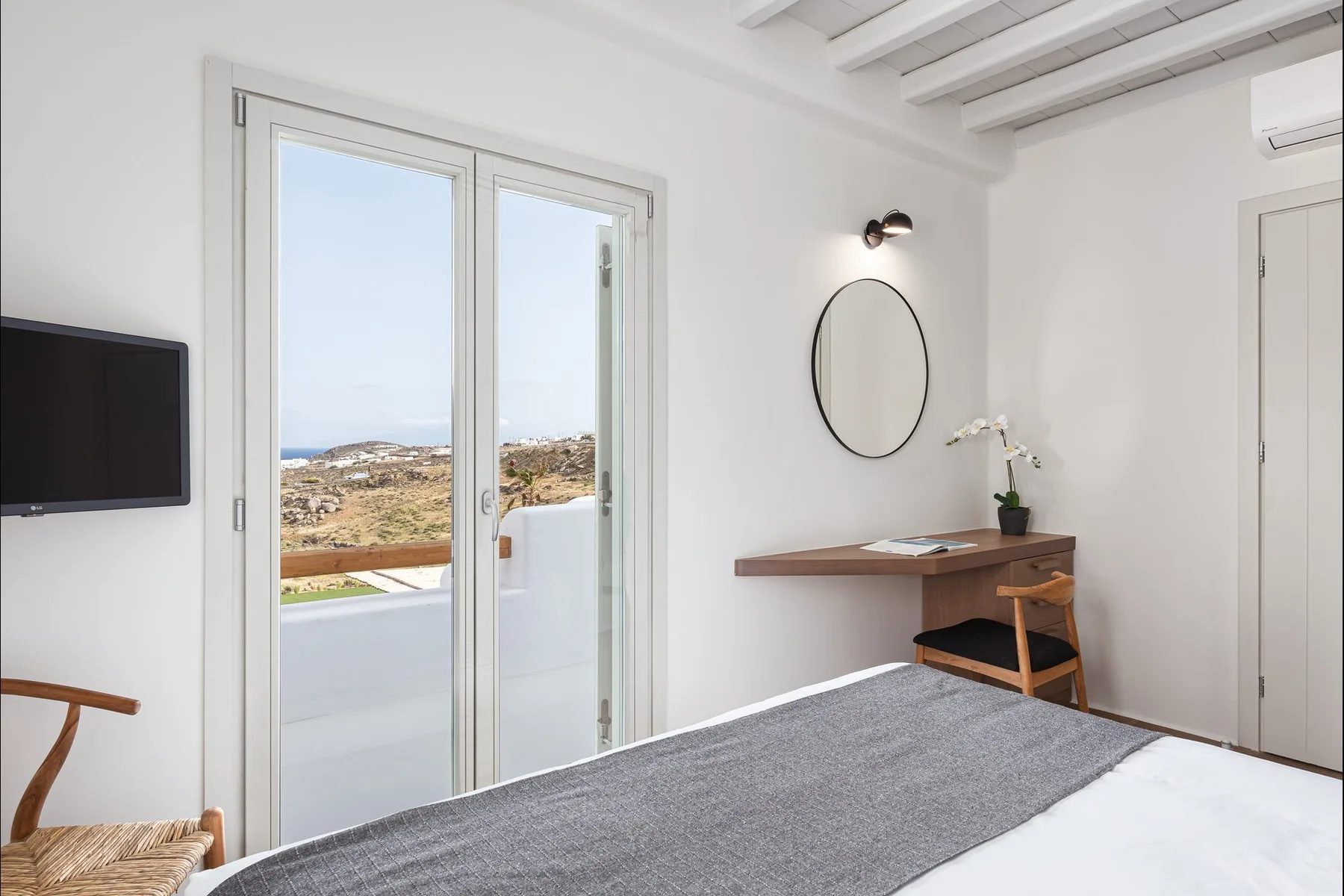 Un dormitorio con cama, escritorio y puertas corredizas de vidrio que dan a un balcón.