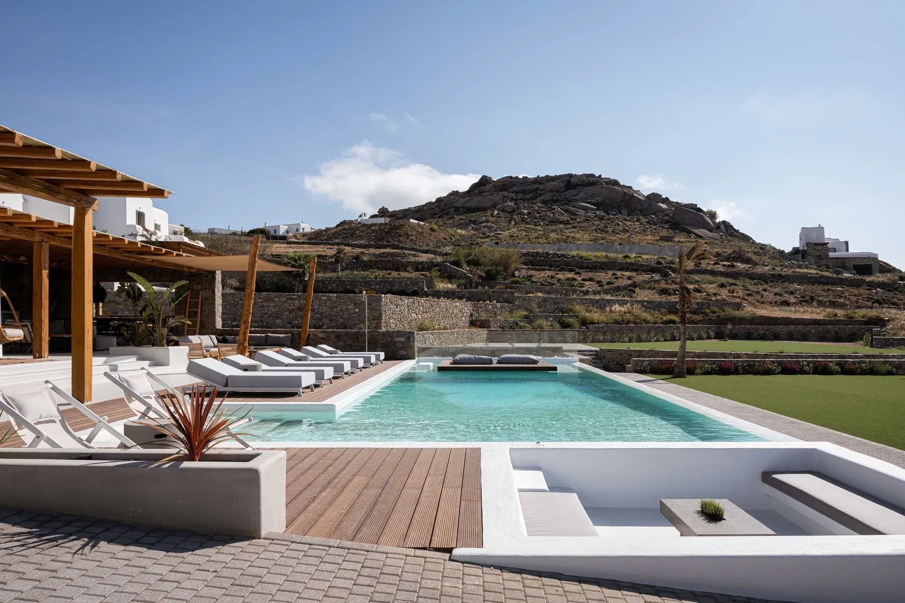 Una piscina al aire libre con asientos para descansar y una terraza pavimentada.