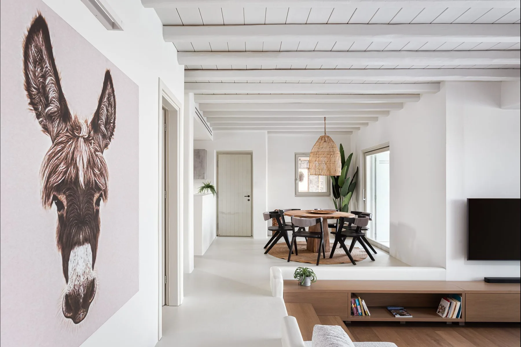 Una luminosa sala-comedor de planta abierta con una mesa de comedor de madera y un televisor.