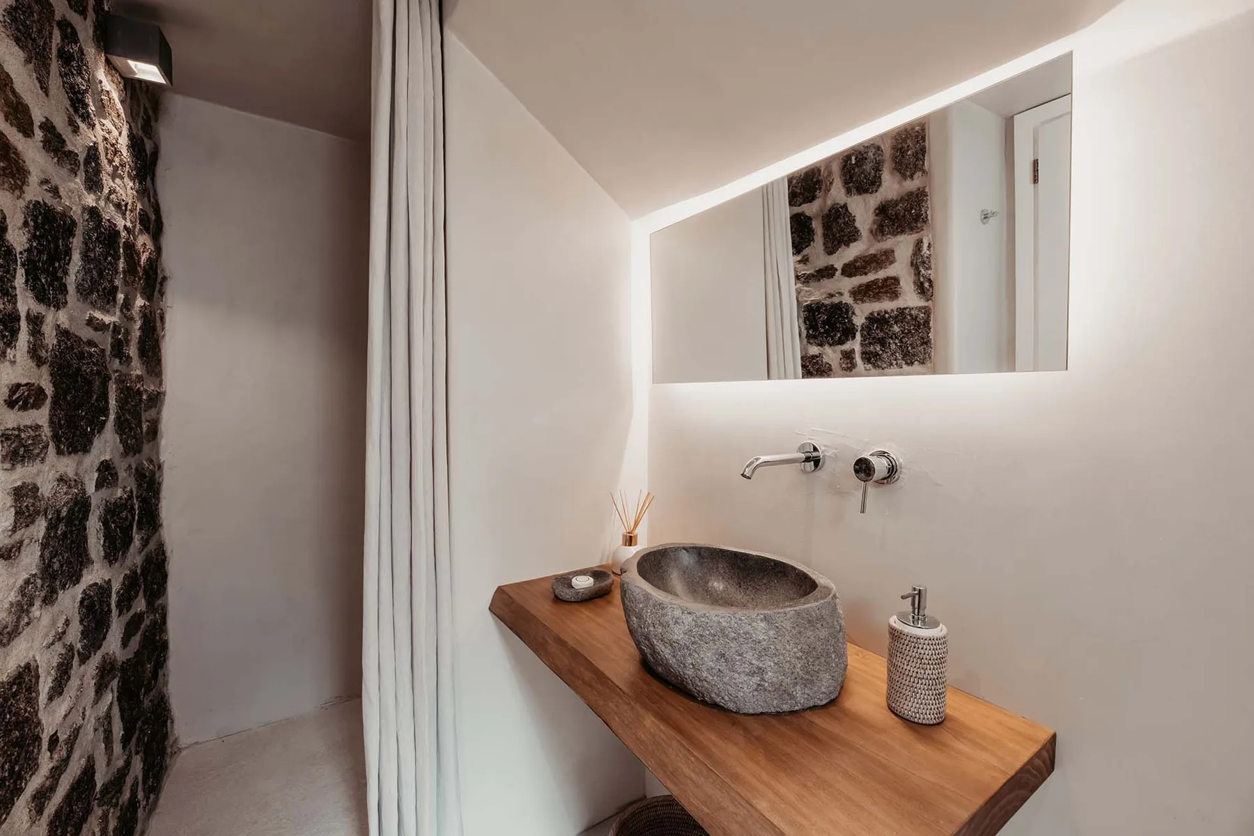 A bathroom vanity with a stone vessel sink and a large mirror.