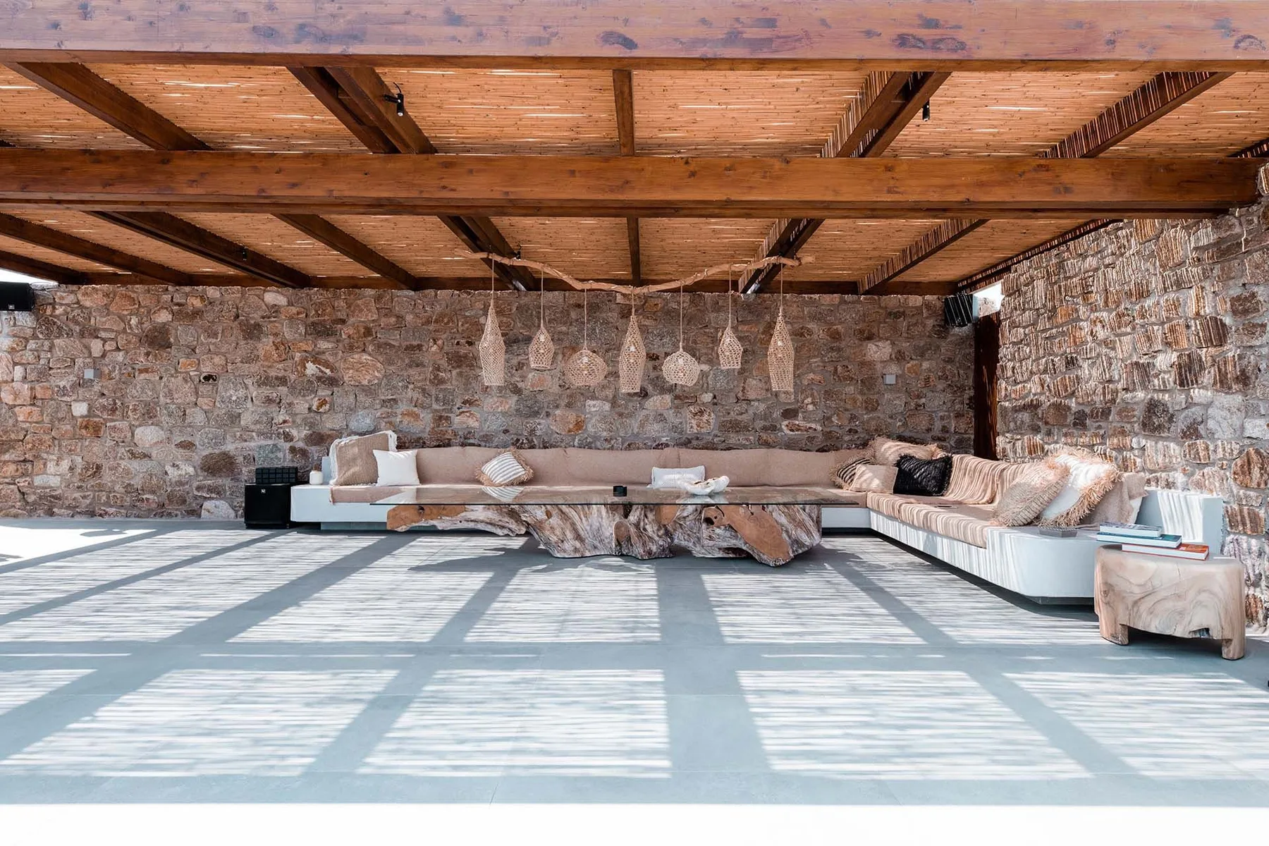 A spacious lounge with sectional seating beneath exposed wooden beams.