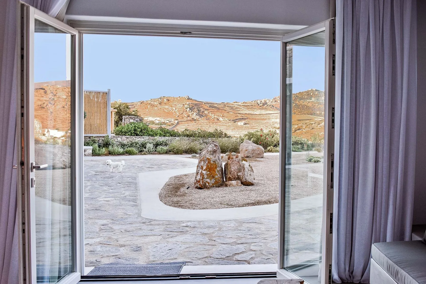 Open glass doors look out onto a stone patio with a landscaped rock feature.