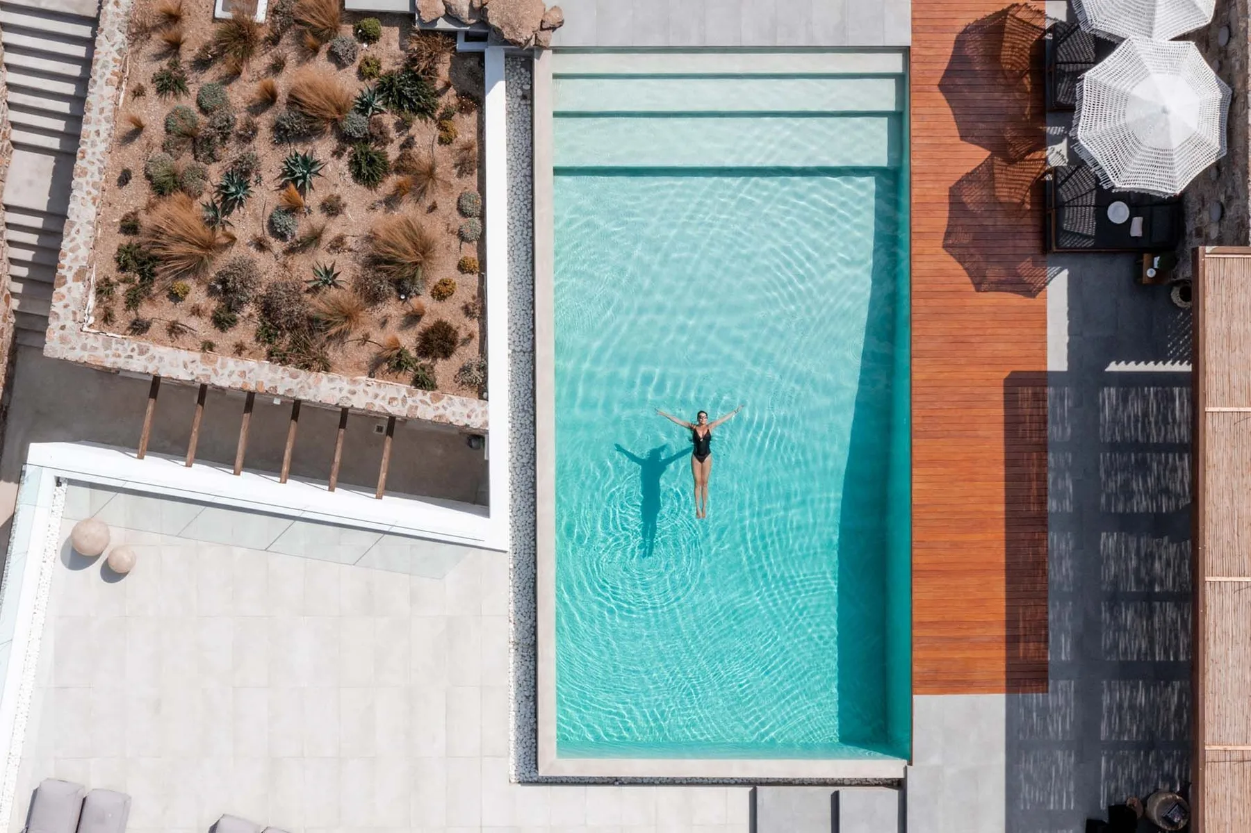 An aerial view of a swimming pool beside a wooden deck and landscaped garden.