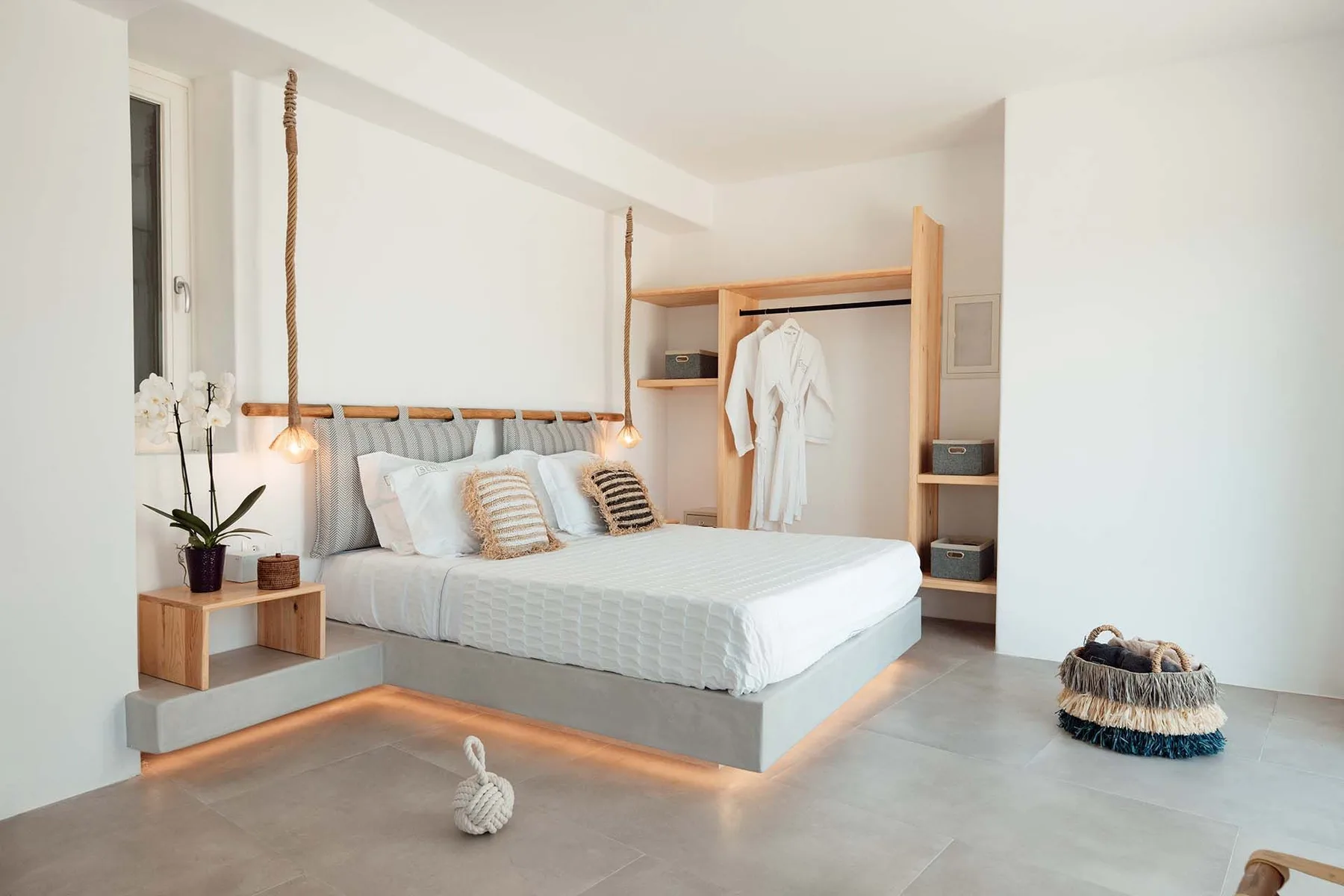 A bright bedroom with a bed and open clothing storage.