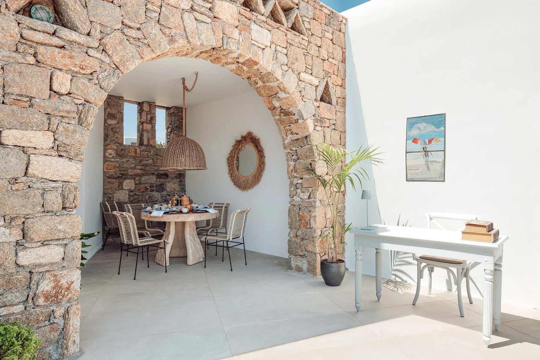 A bright dining area with a round table beneath a stone arch.