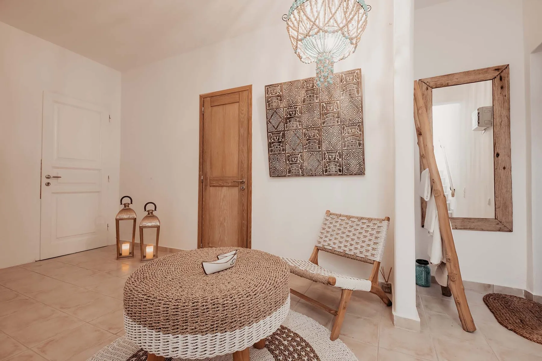 A bright sitting area with a woven round table and a wooden lounge chair.