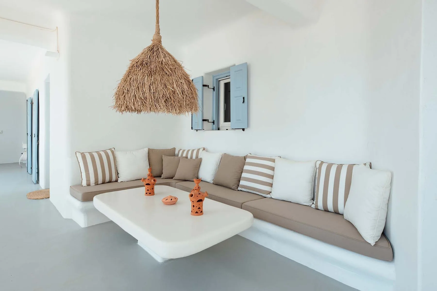 A bright lounge features a built-in seating area with striped cushions and a low table.