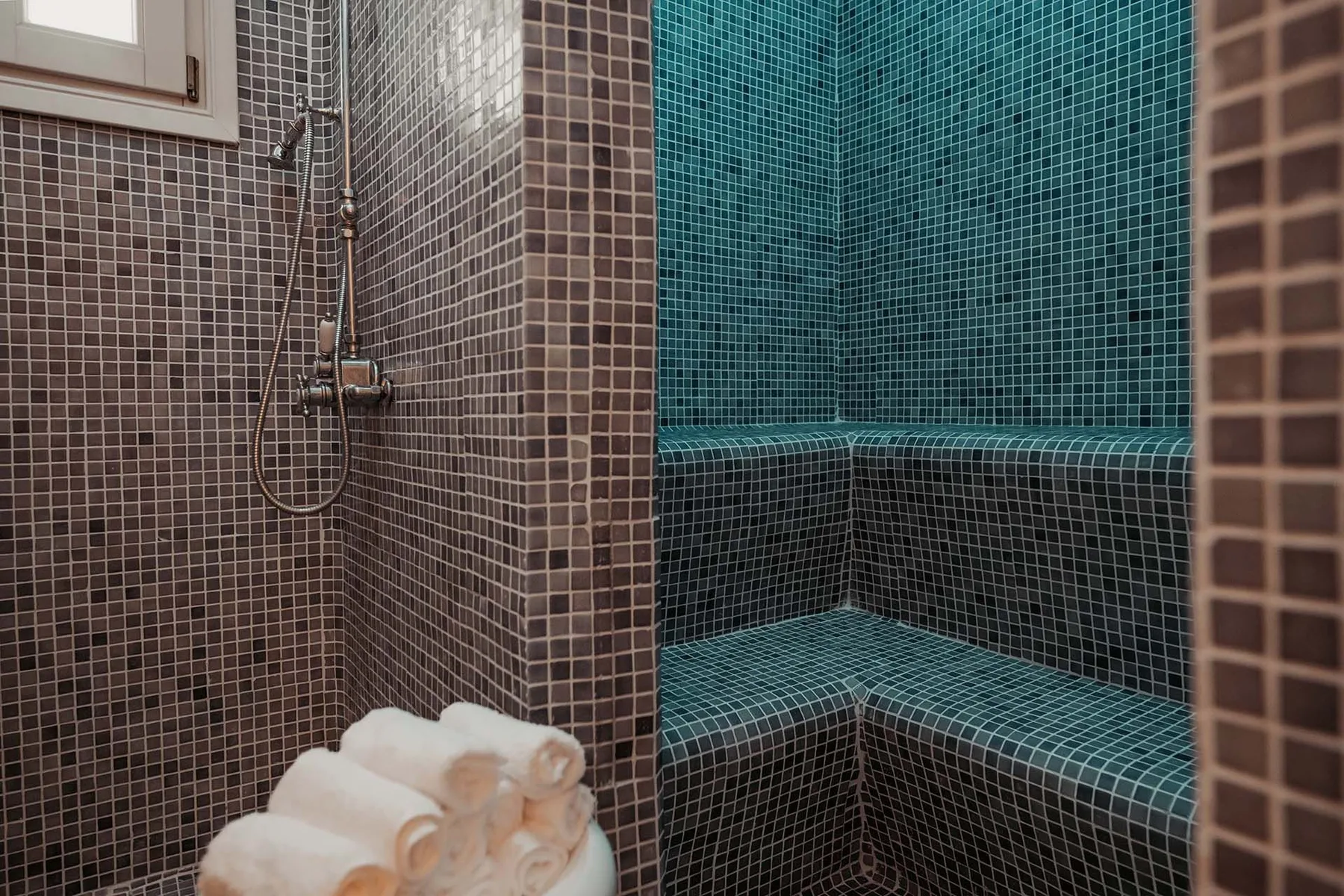 A tiled bathroom with a shower and a built-in bench.