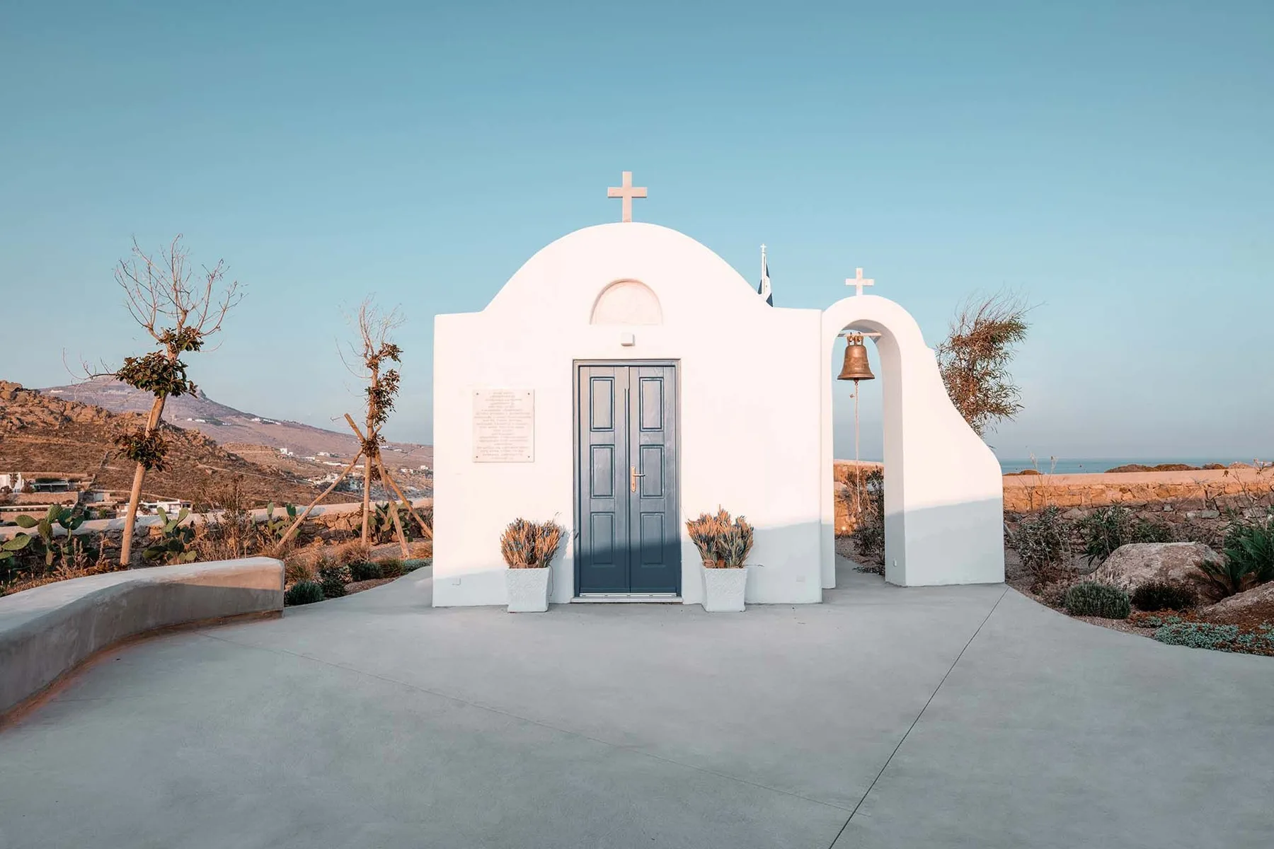 A small white chapel stands beside an open, dry landscape.