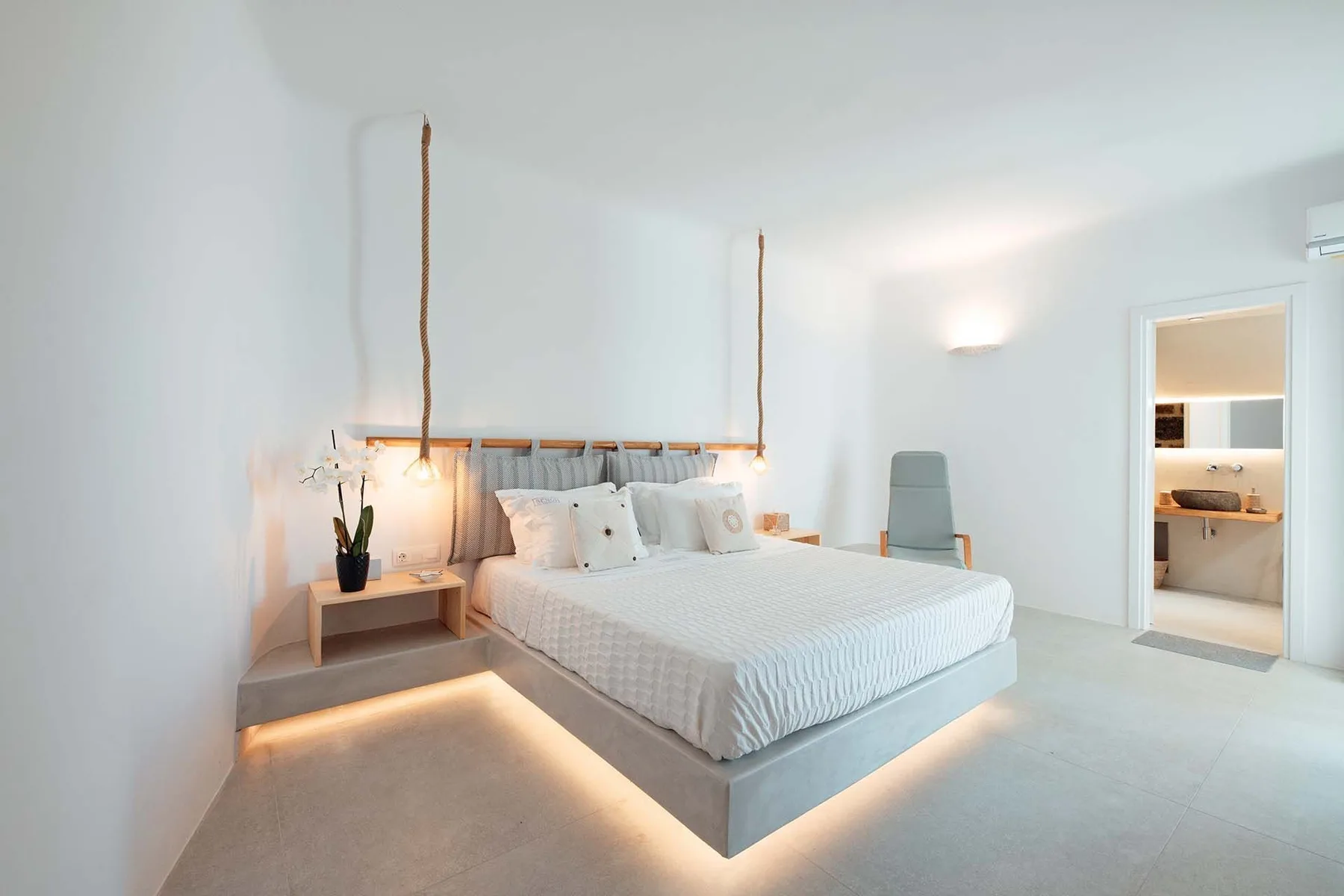 A bright bedroom with a neatly made bed and a doorway to a bathroom.