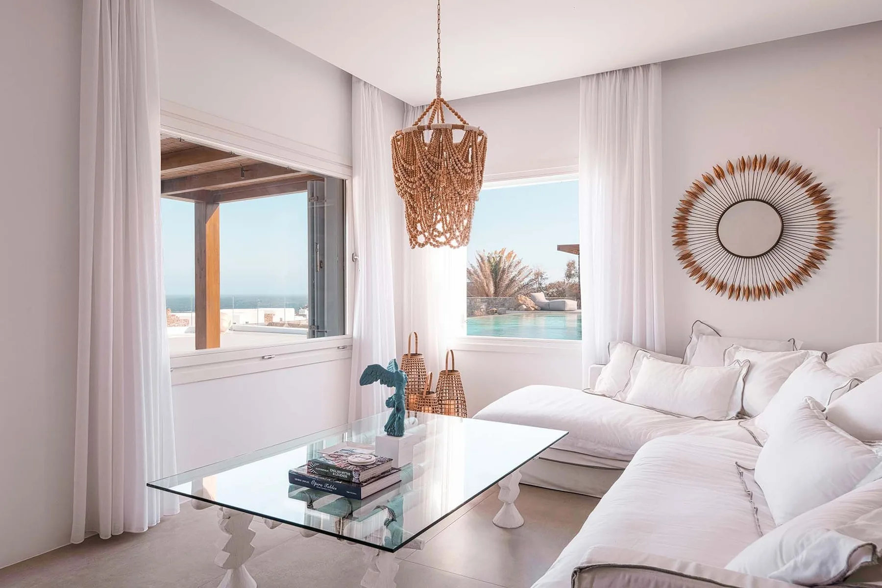 A bright living room with white seating and a glass coffee table.