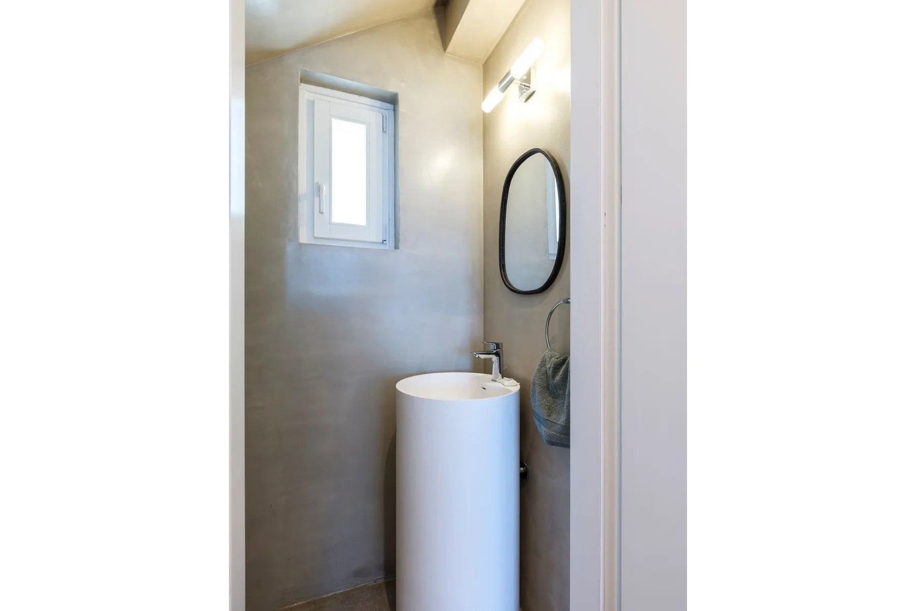 A compact bathroom with a freestanding sink and wall mirror.