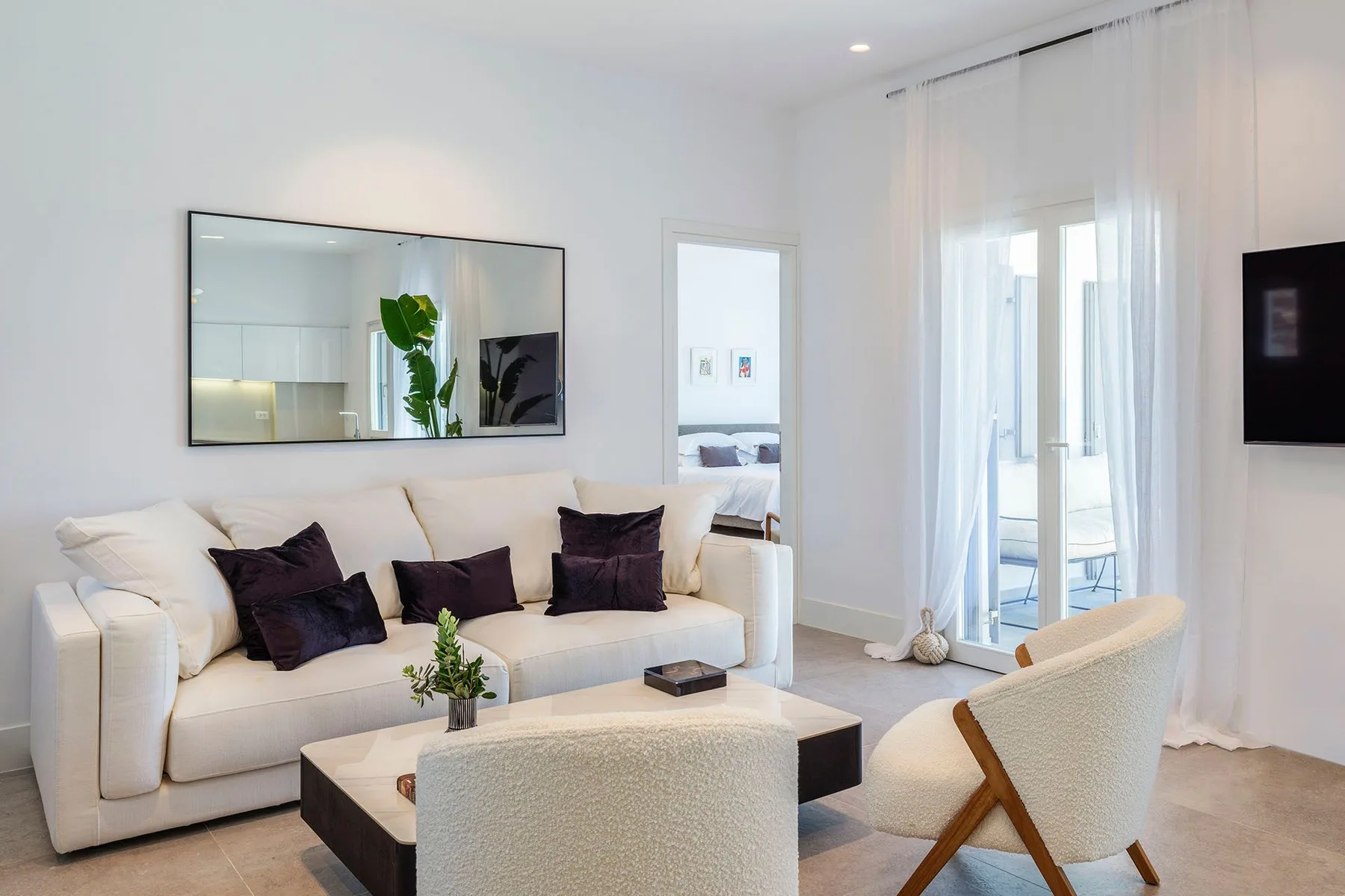 A bright living room with a cream sofa and a glass coffee table.
