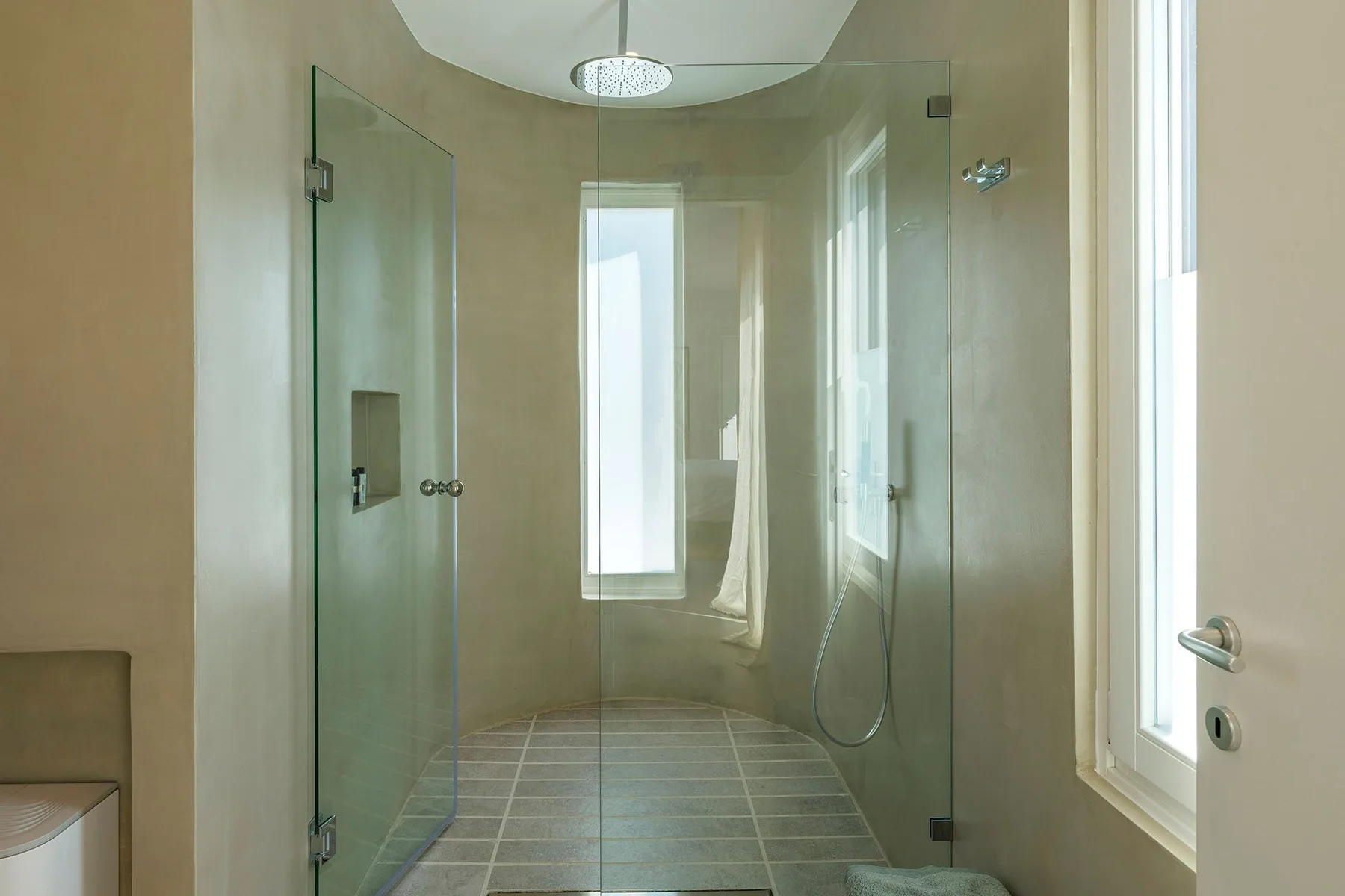 A bright bathroom with a glass shower and large windows.