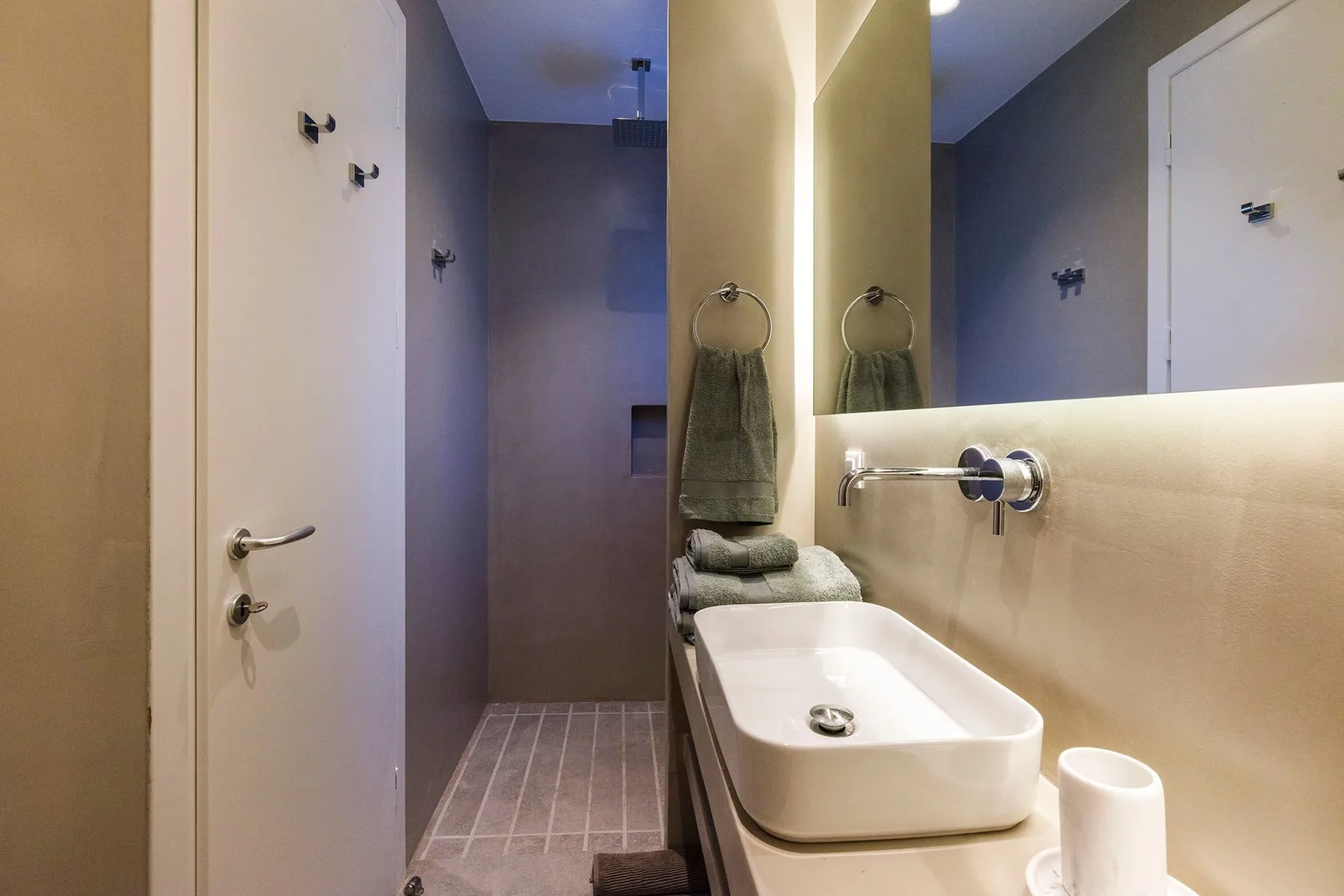 A bathroom with a sink, mirror, and shower area.