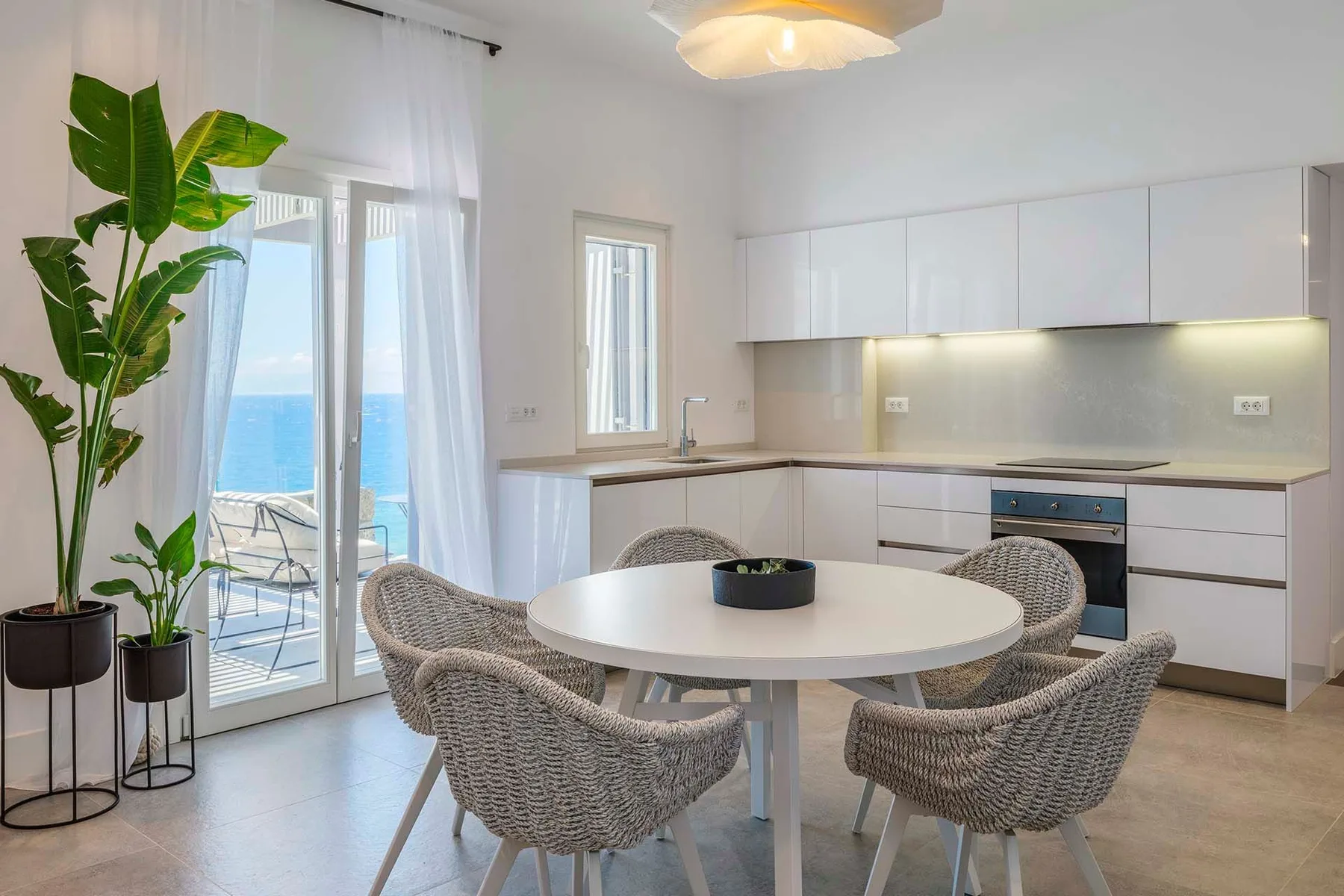 A bright kitchen and dining area with a round table beside glass doors opening to a balcony.