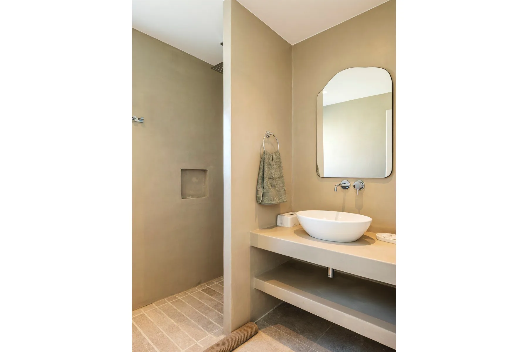 A bathroom with a walk-in shower area and a sink beneath a mirror.