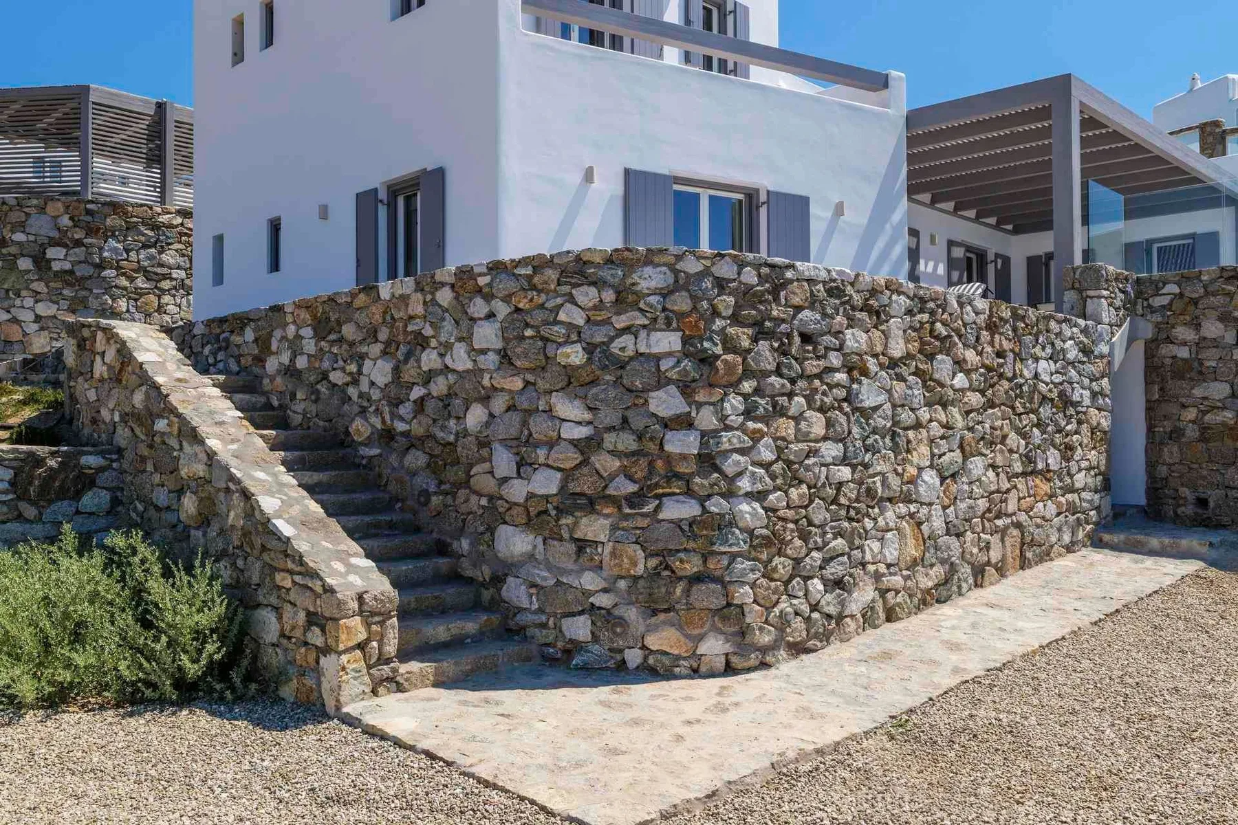 A white building stands behind stone retaining walls and outdoor steps.