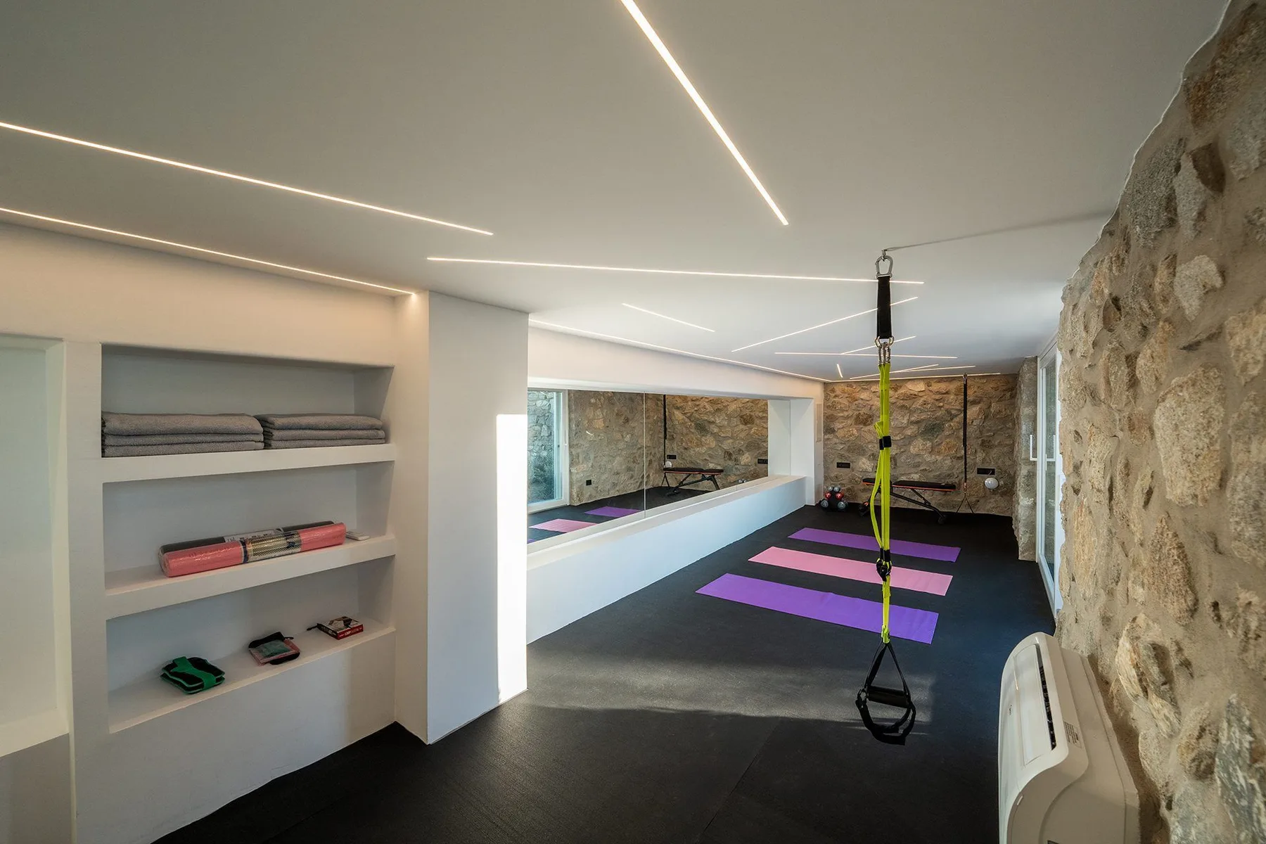 A modern exercise room with colorful floor mats and a stone wall.