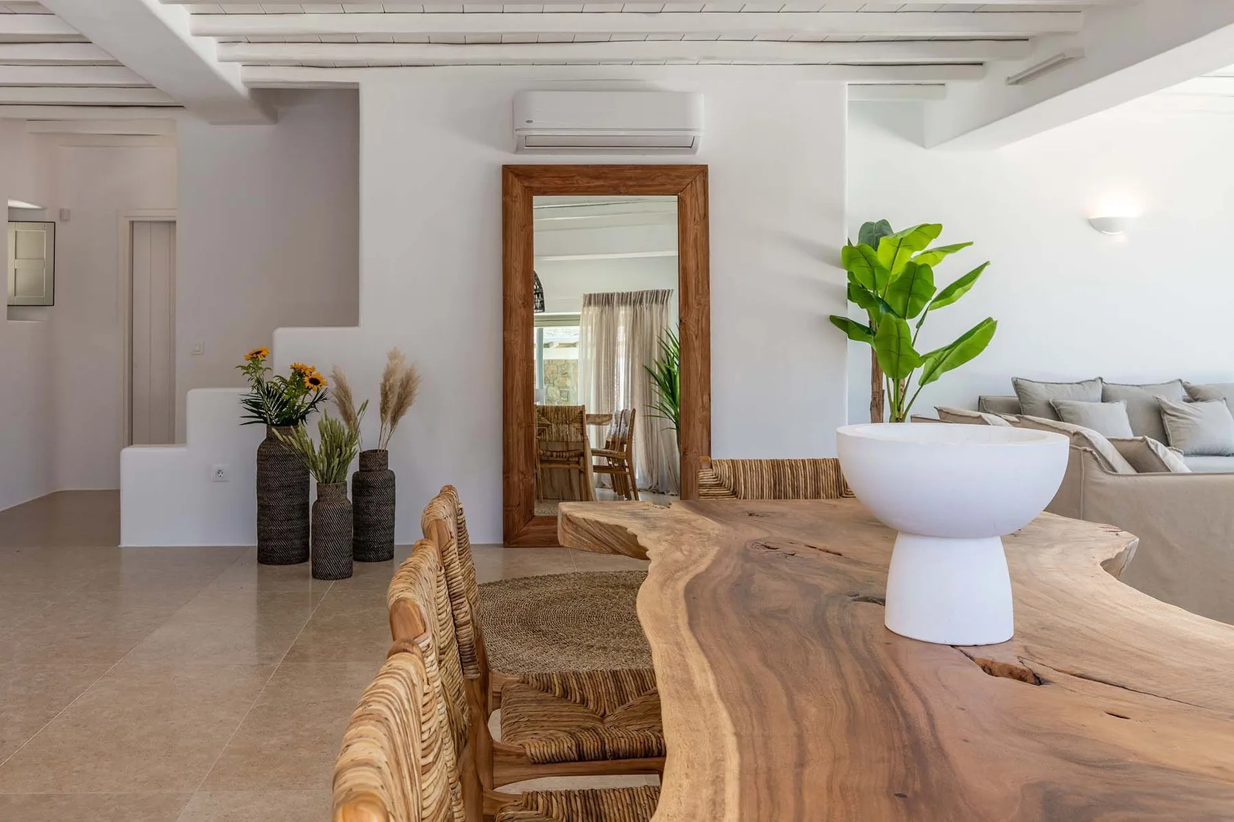 A bright open-plan living area with a wooden dining table and seating.
