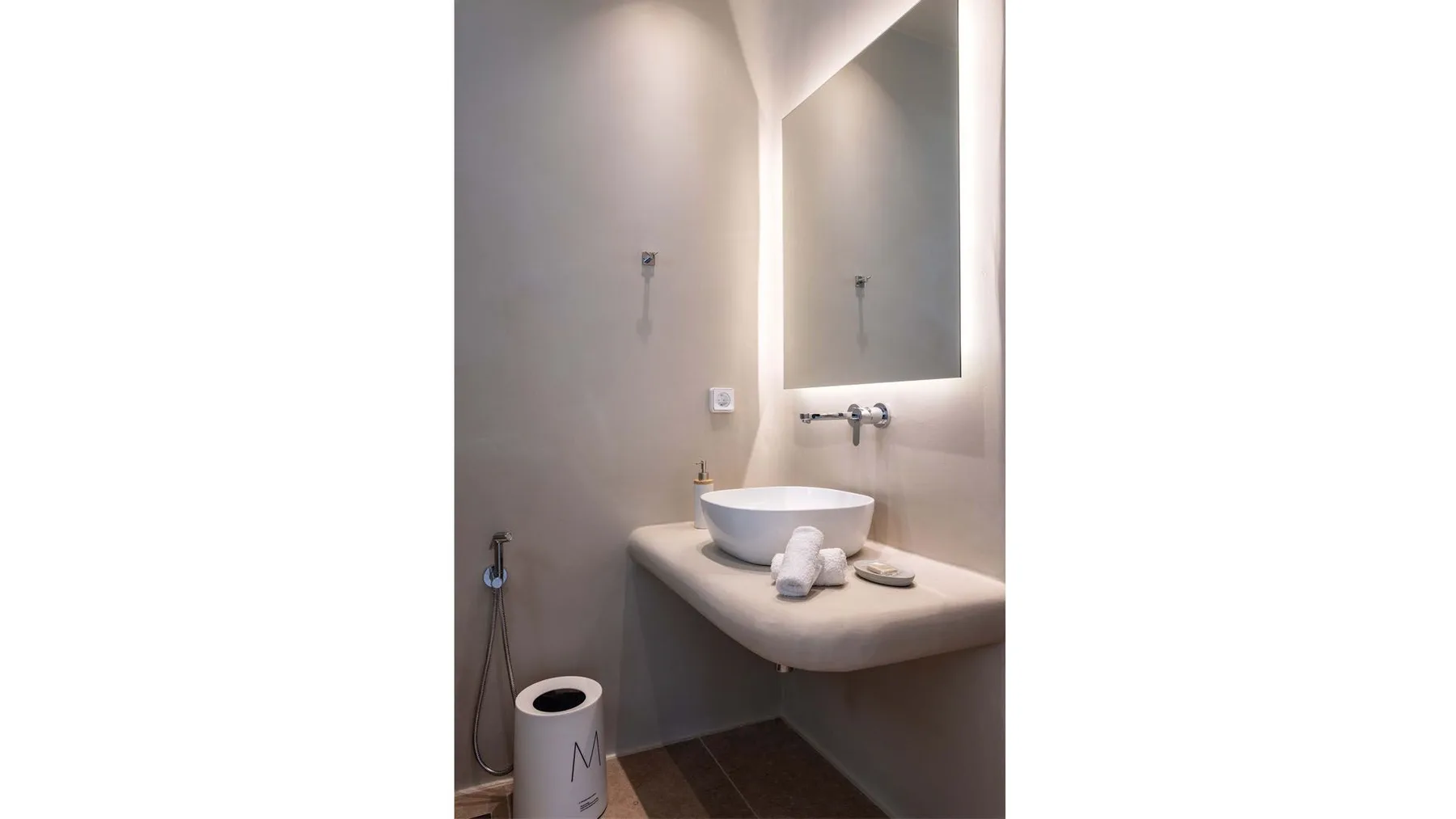A bathroom vanity with a vessel sink, wall mirror, and folded towels.