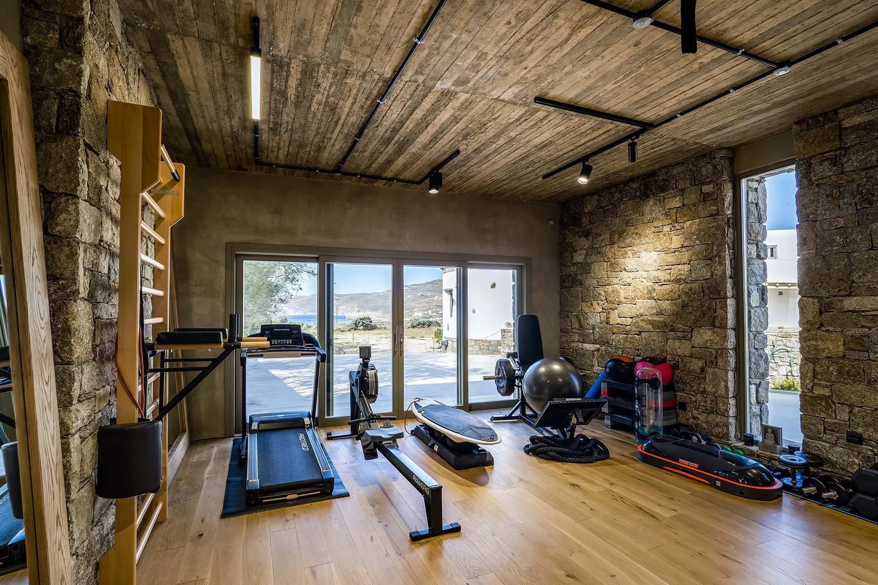 Shared amenity: A workout room with exercise machines and weights beside large windows.