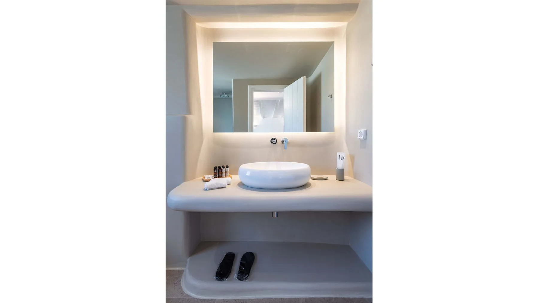 A bathroom vanity with a white basin beneath a large mirror.