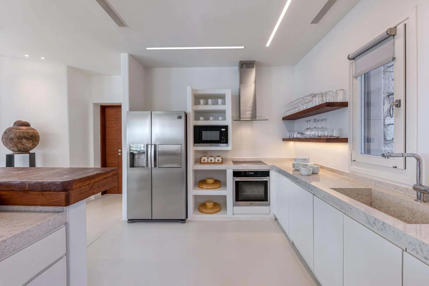 A bright modern kitchen with white cabinetry, stainless steel appliances, and a central island.