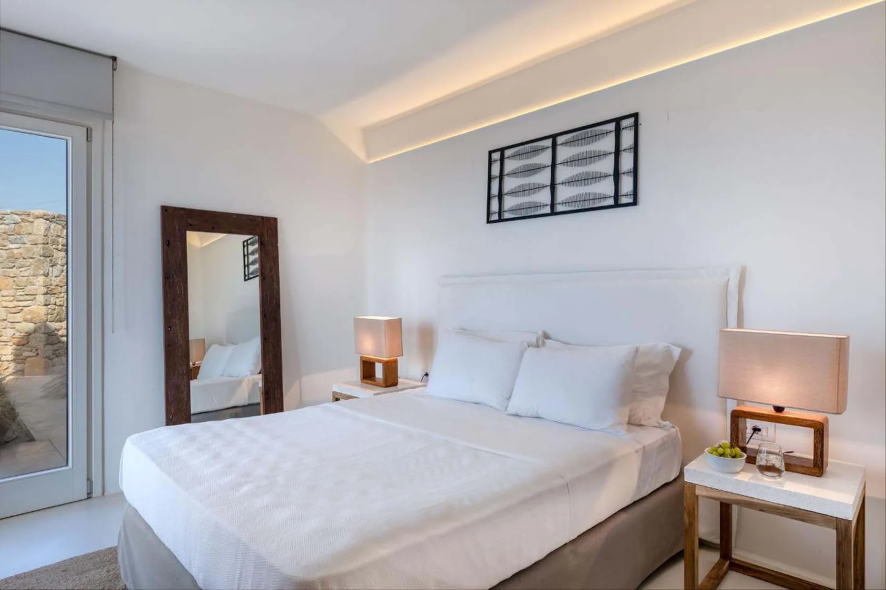 A bright bedroom with a neatly made bed and matching bedside tables.