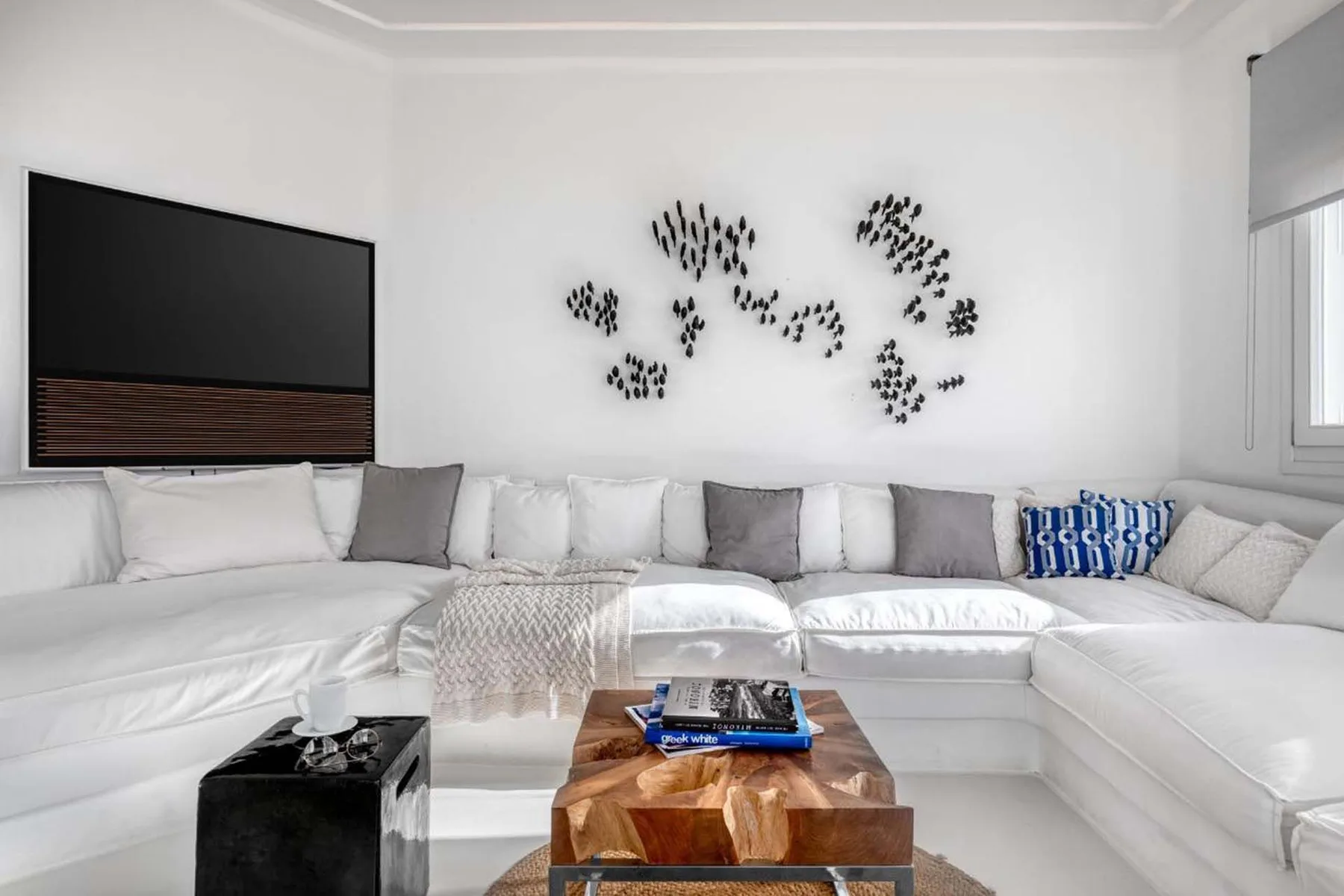 A bright living room with a white sectional and a wall-mounted television.