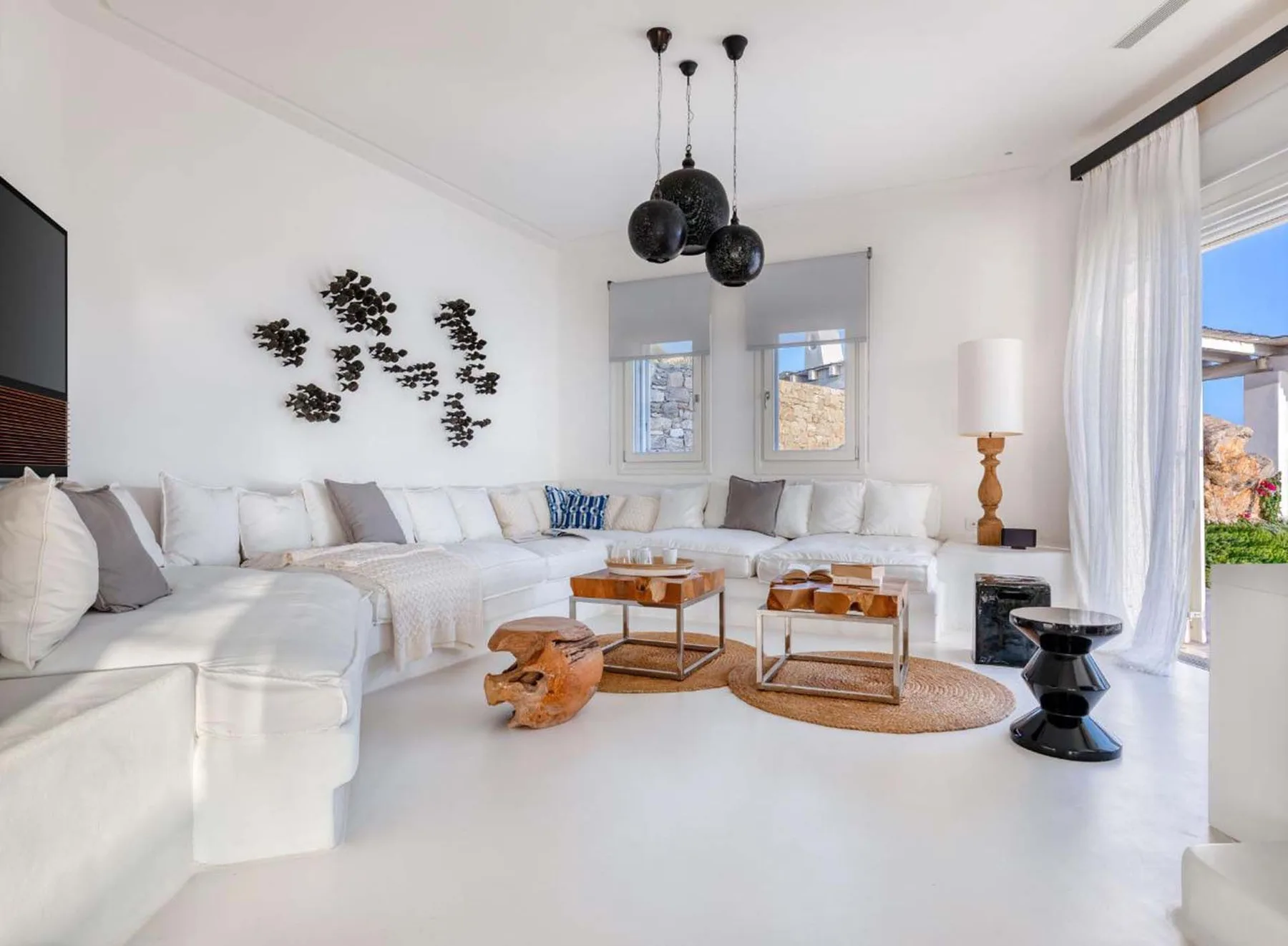 A bright living room has white seating around a low coffee table and a round rug.