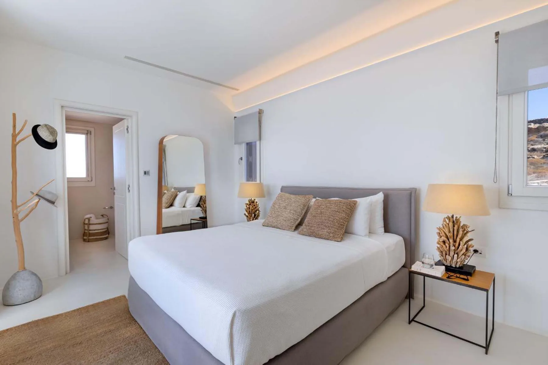 A bright bedroom with a neatly made bed and windows.