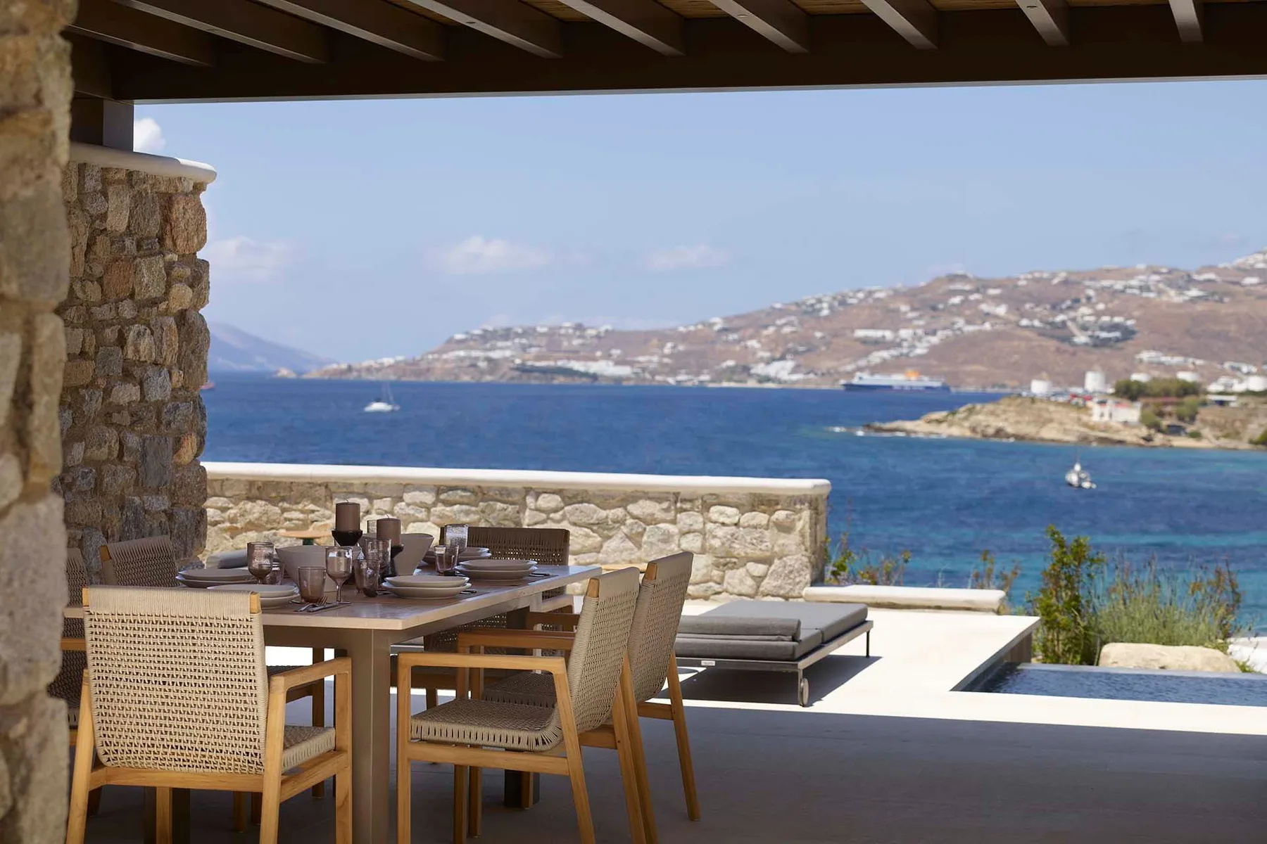 A seaside terrace with an outdoor dining table and views across the water.