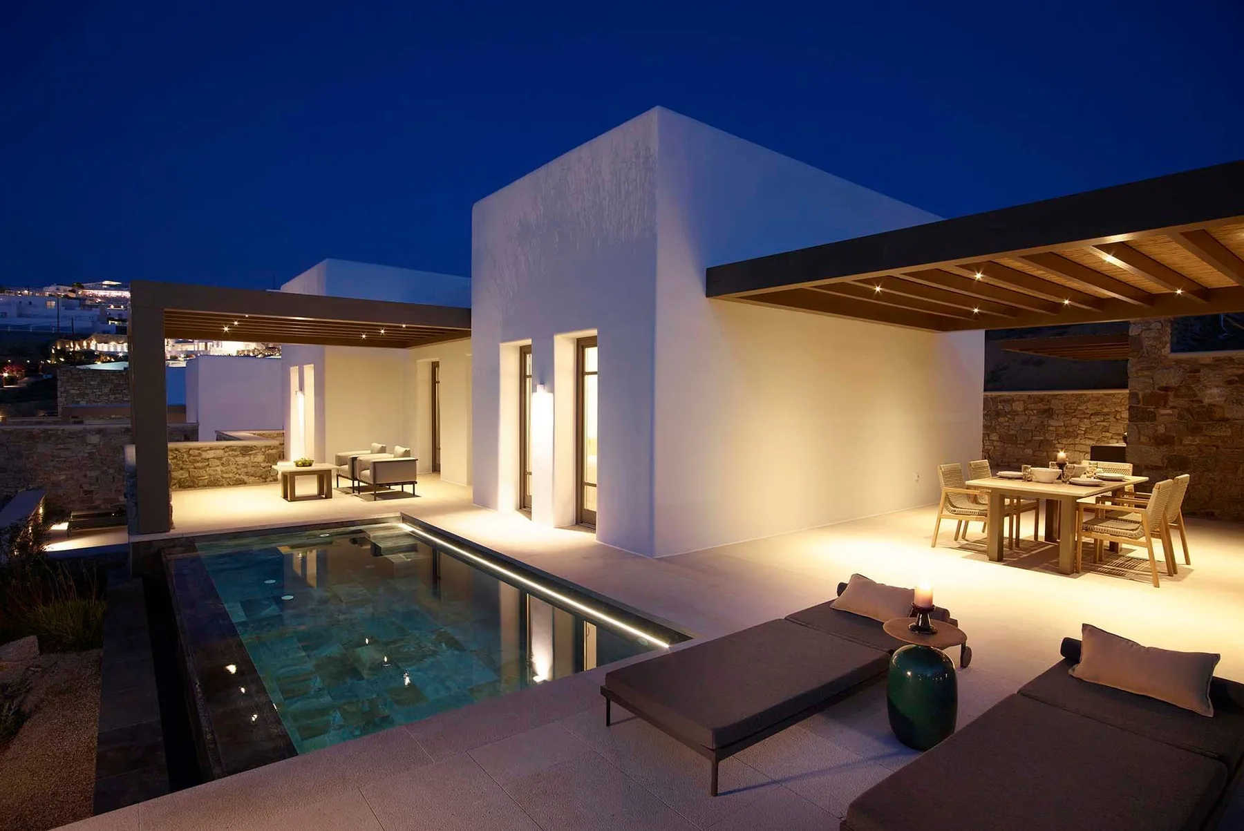 Modern patio at dusk with a pool, lounge seating, and a dining area.