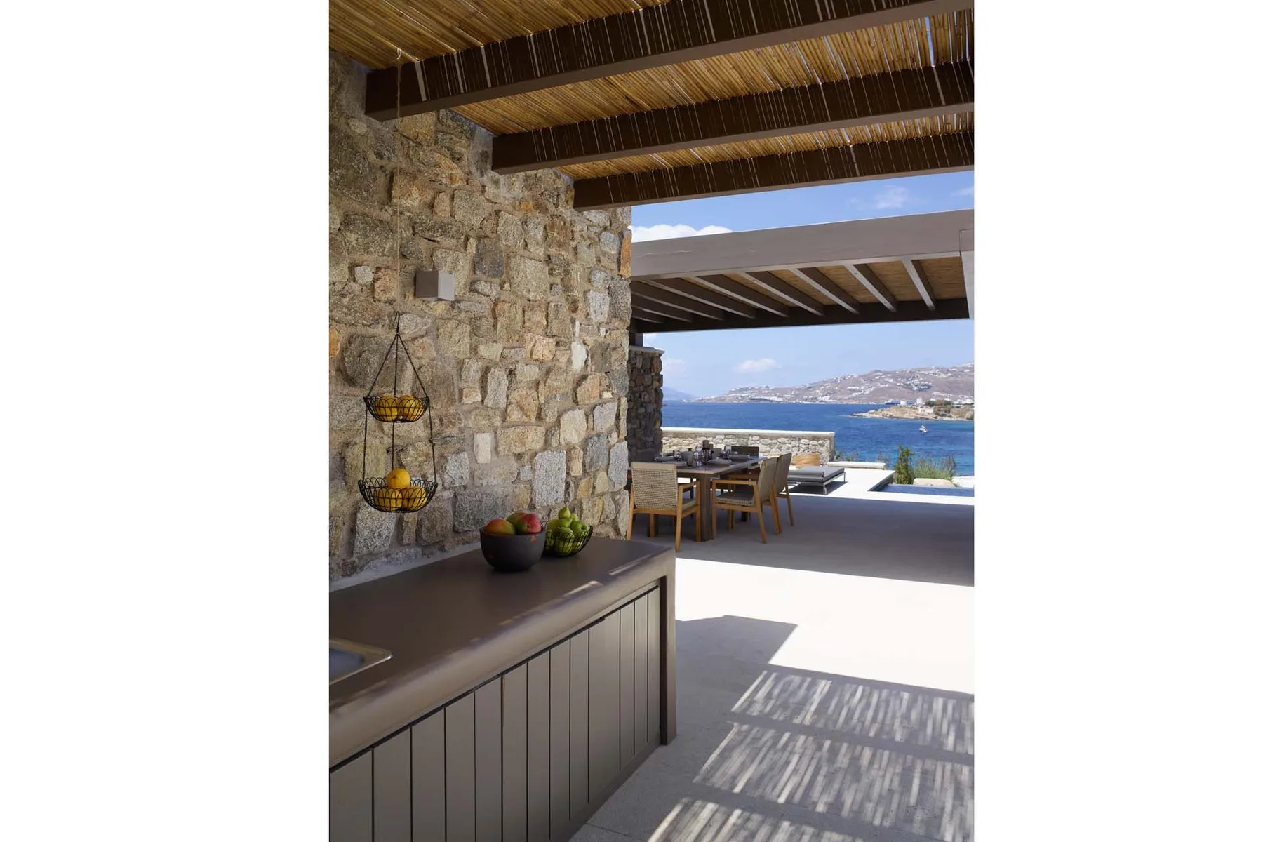 An open-air kitchen and dining area overlooks the sea.