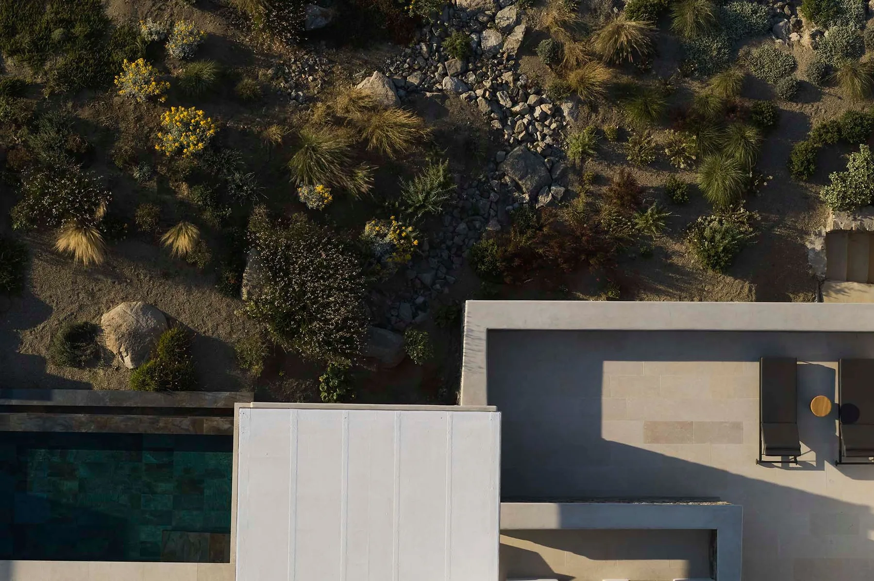 An aerial view shows a modern building beside a landscaped garden with a rocky path.