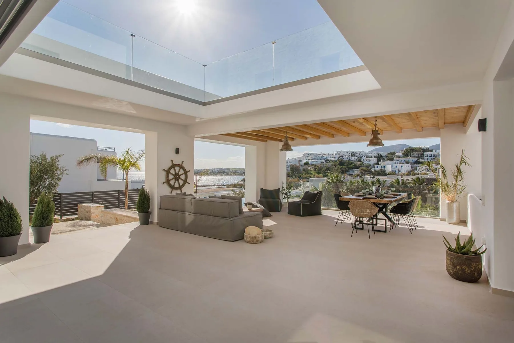 An open-air living and dining area overlooks a coastal landscape.