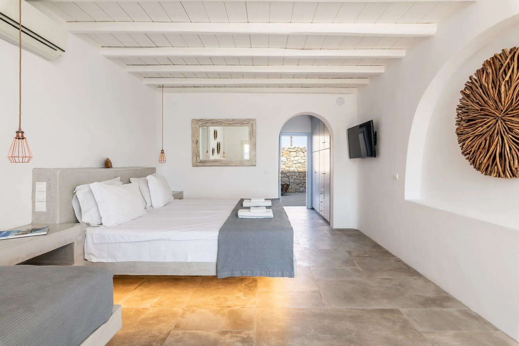 A bright bedroom with a large bed and an arched doorway.