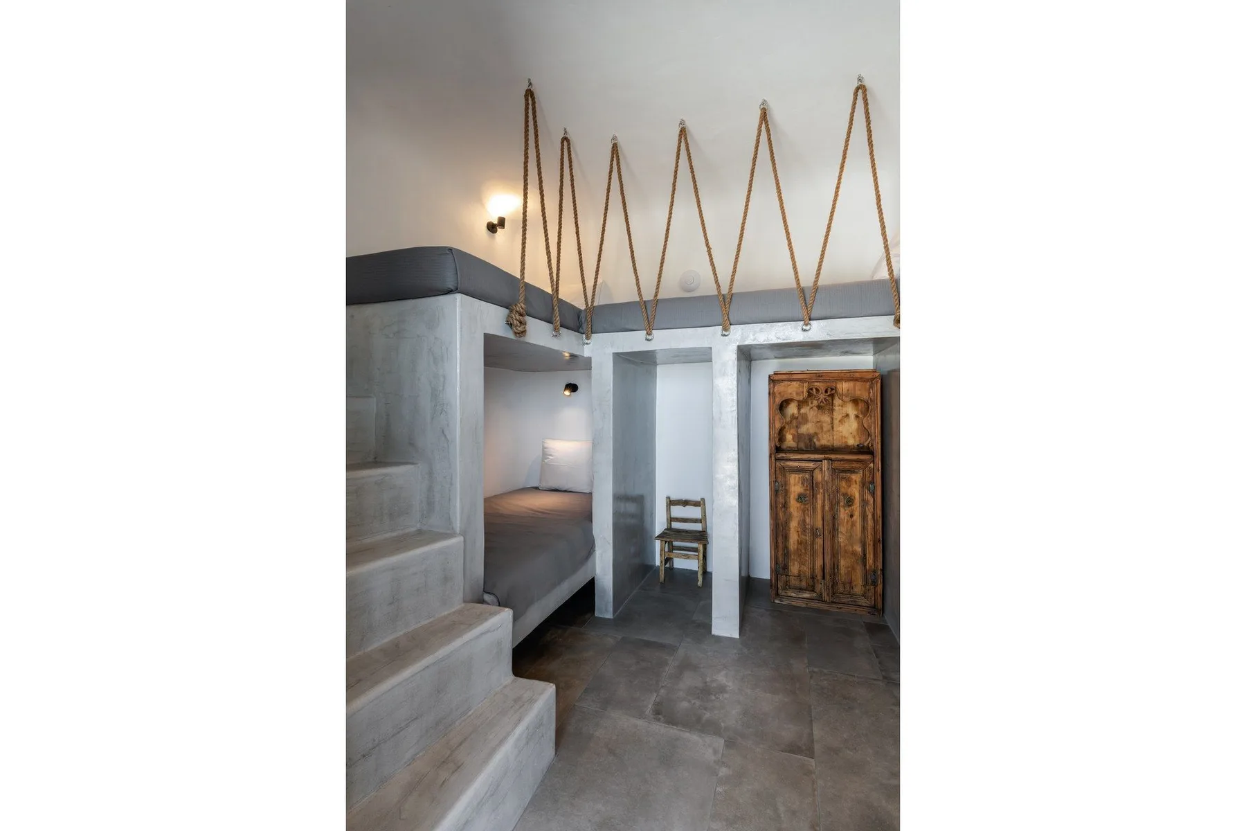 A loft-style room with a built-in bed, concrete stairs, and a wooden door.